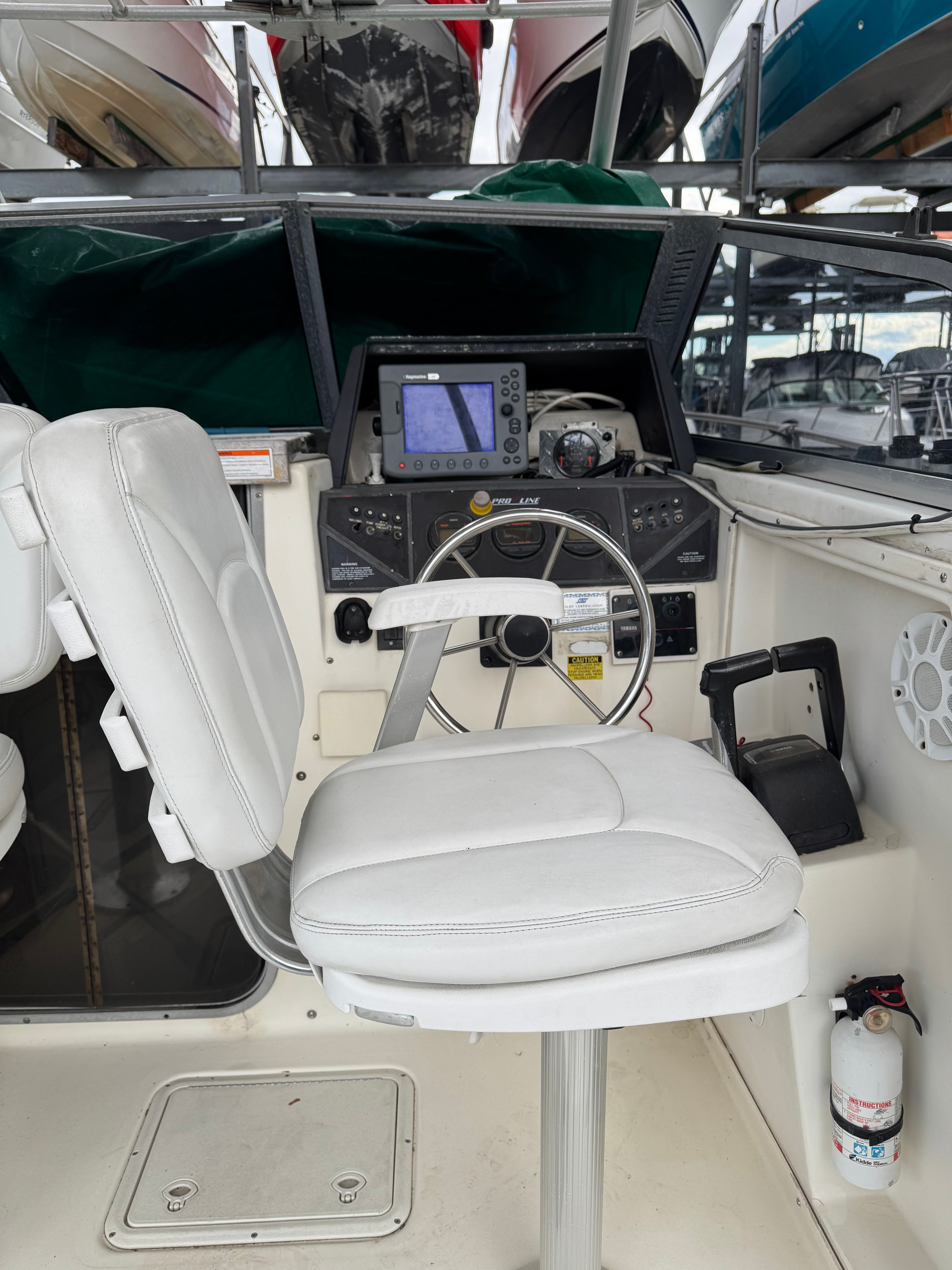 Interior view of a boat with a white seat and steering console.