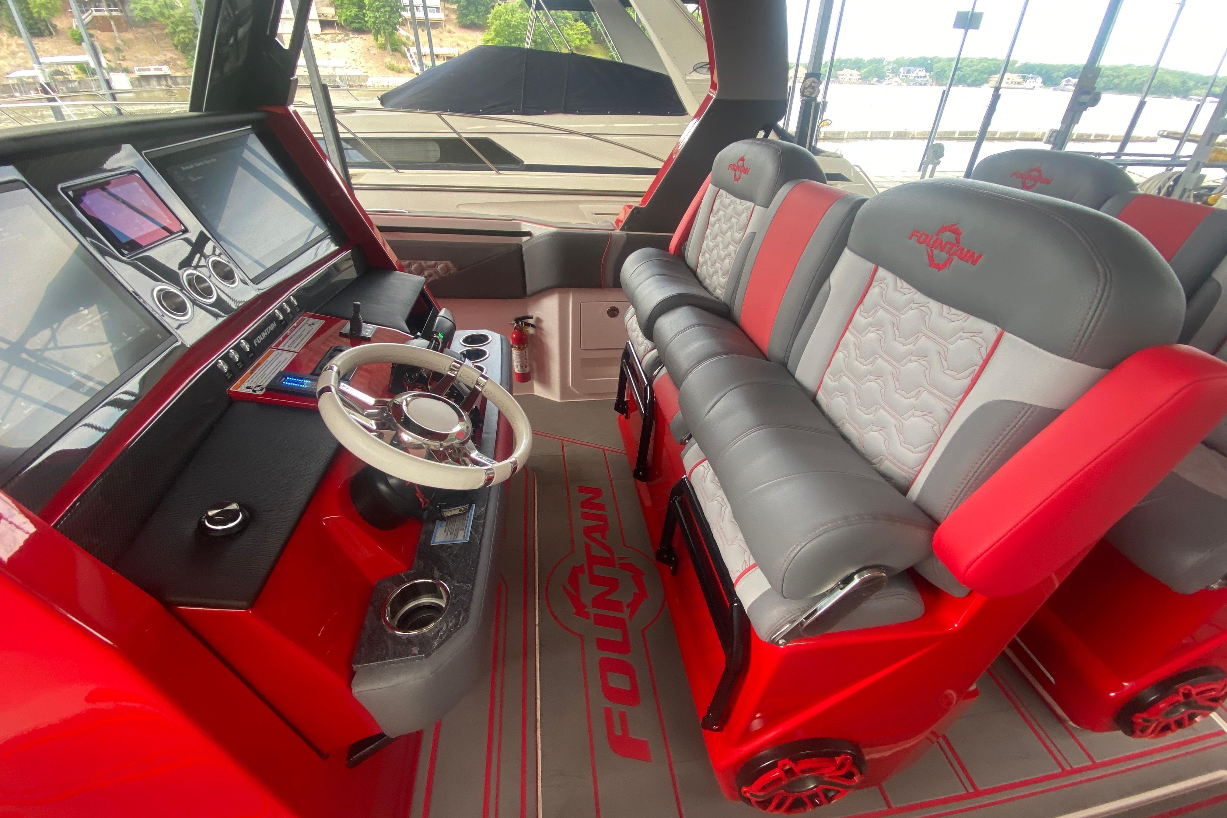 2025 Fountain 38 SCX boat interior with red and gray seating, modern dashboard, and steering wheel.