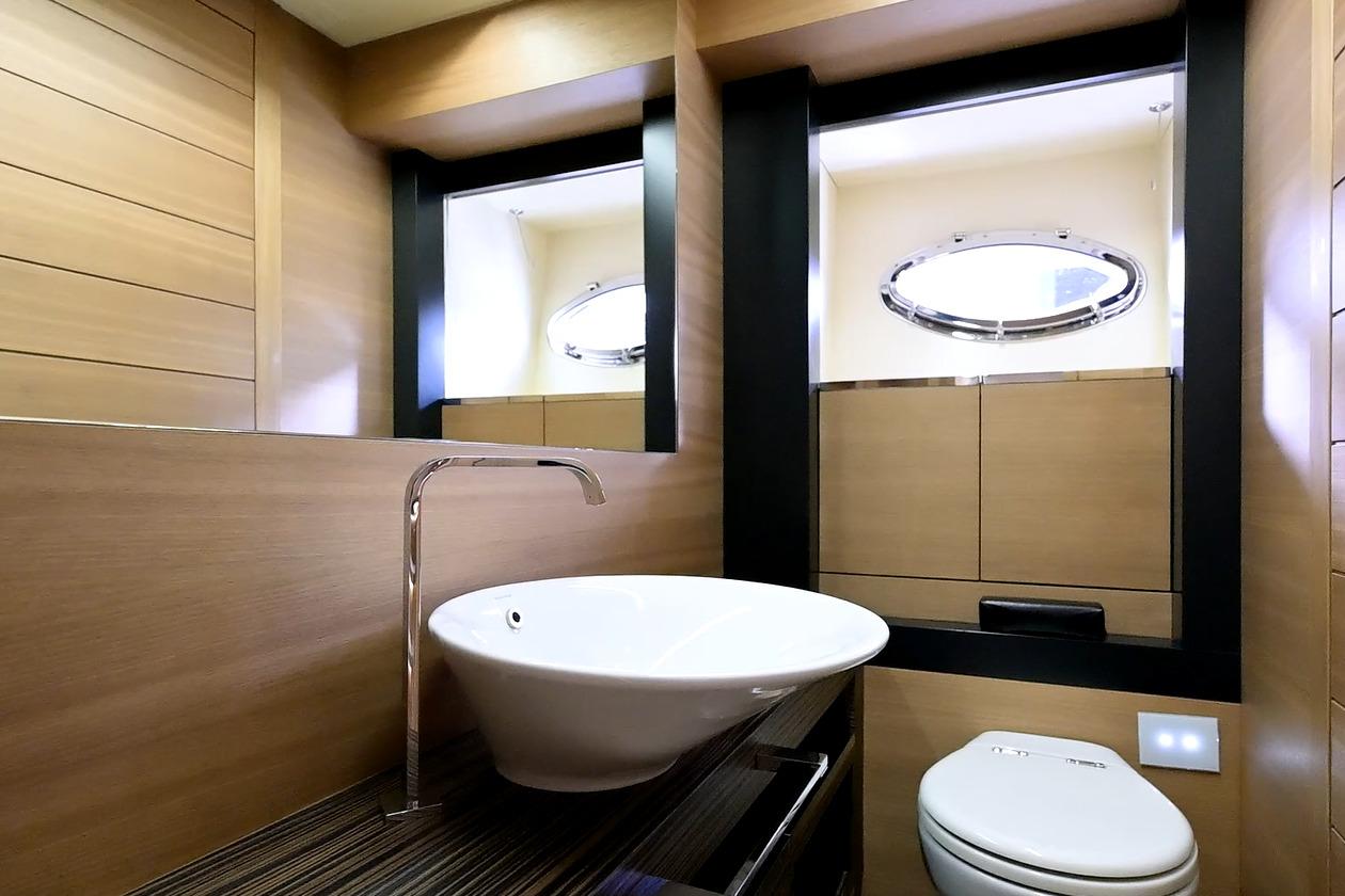 Luxurious bathroom interior of 2015 Pershing 92 yacht with modern fixtures and porthole window.