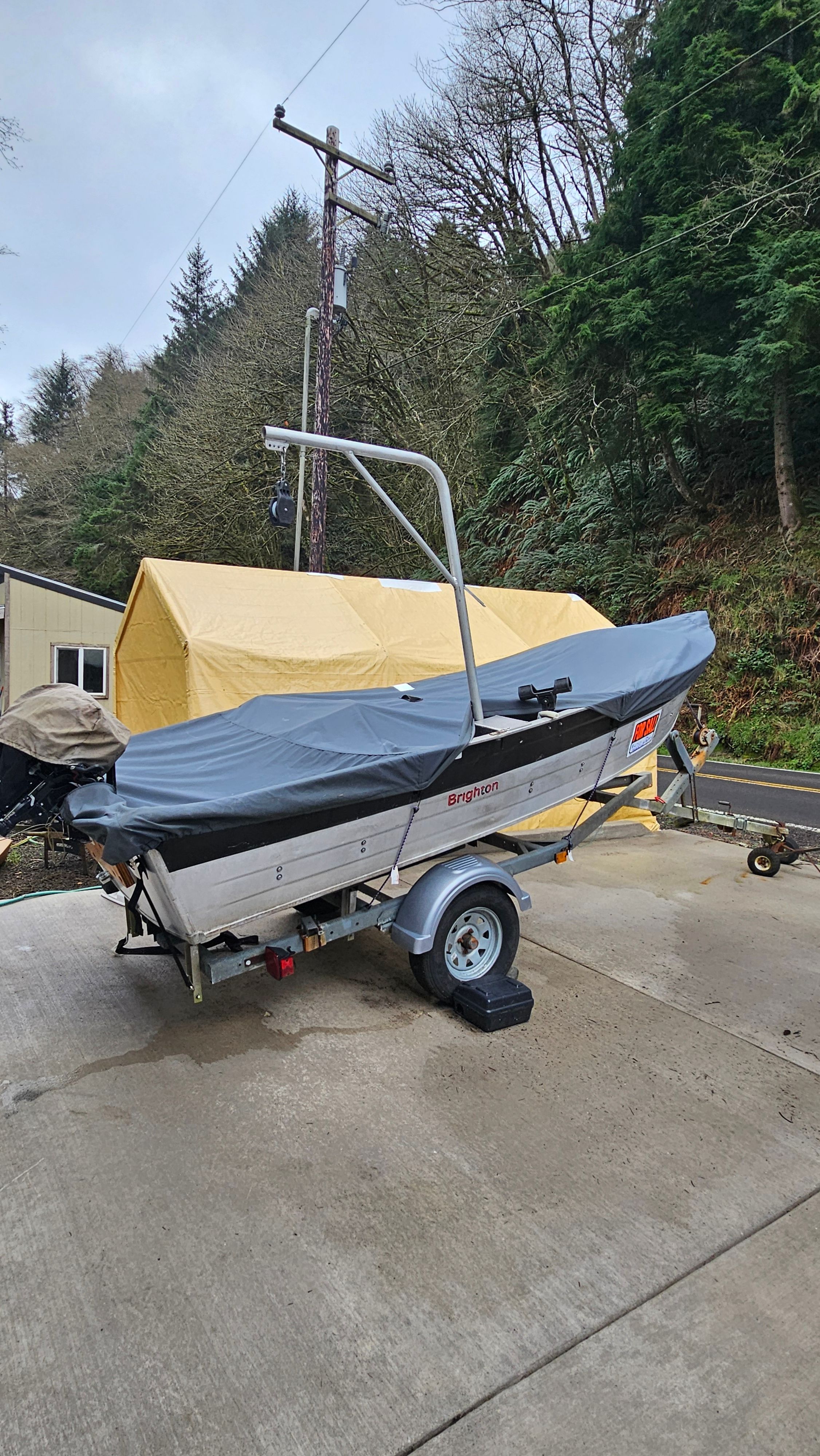 A 1988 aluminum fishing boat on a trailer, surrounded by trees and a yellow tent.