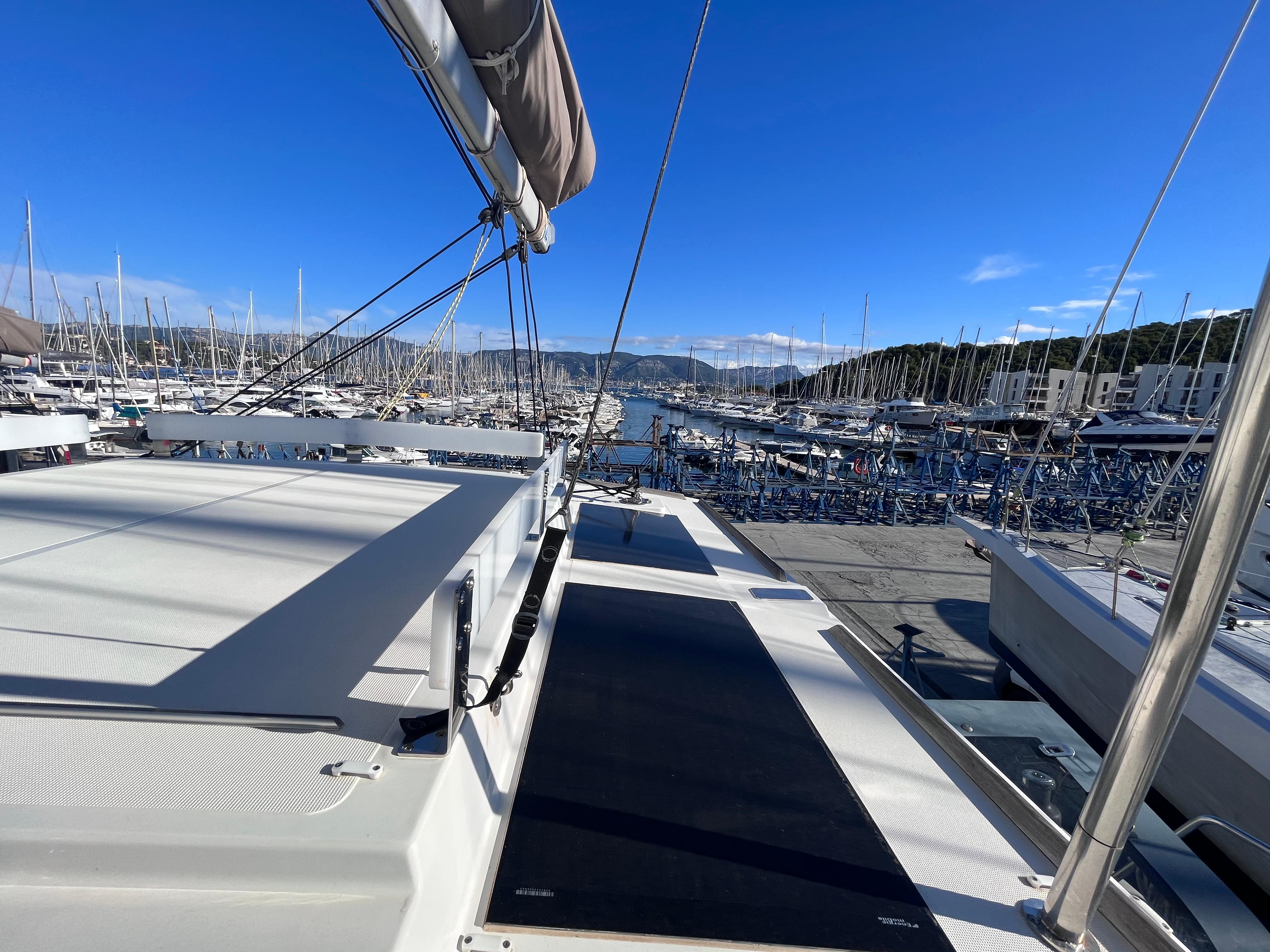 2021 Bali 4.6 catamaran docked in a sunny marina, surrounded by sailboats.