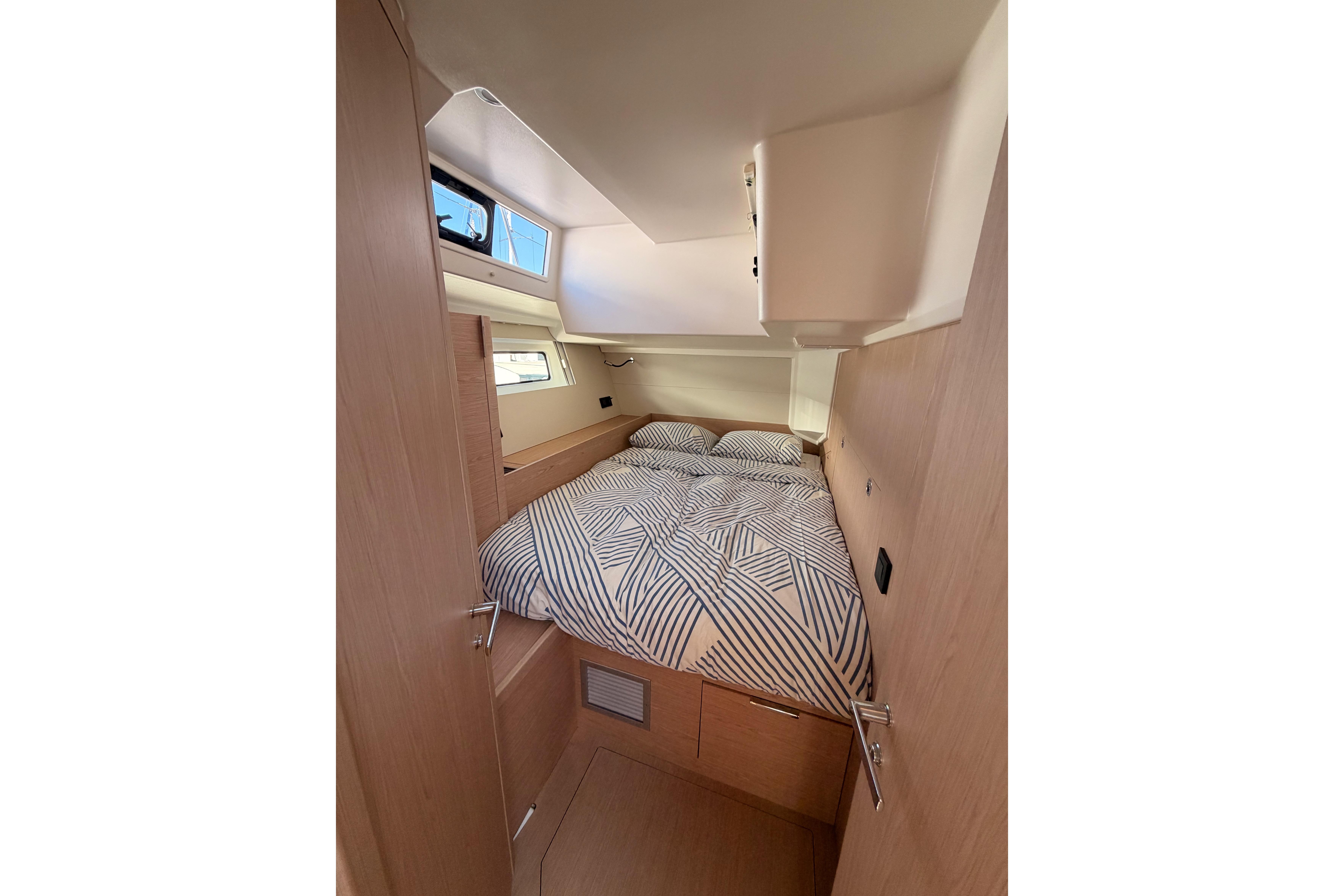 Cozy cabin interior of 2022 Beneteau Oceanis Yacht 54 with patterned bedding.
