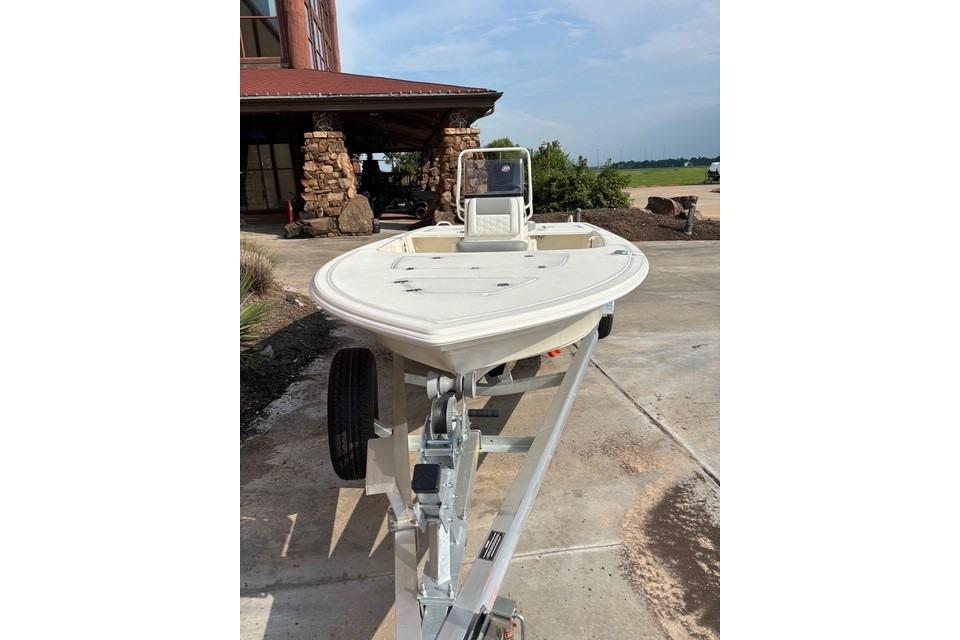 2026 Mako 18 Pro Skiff on trailer, parked outdoors near a rustic building.
