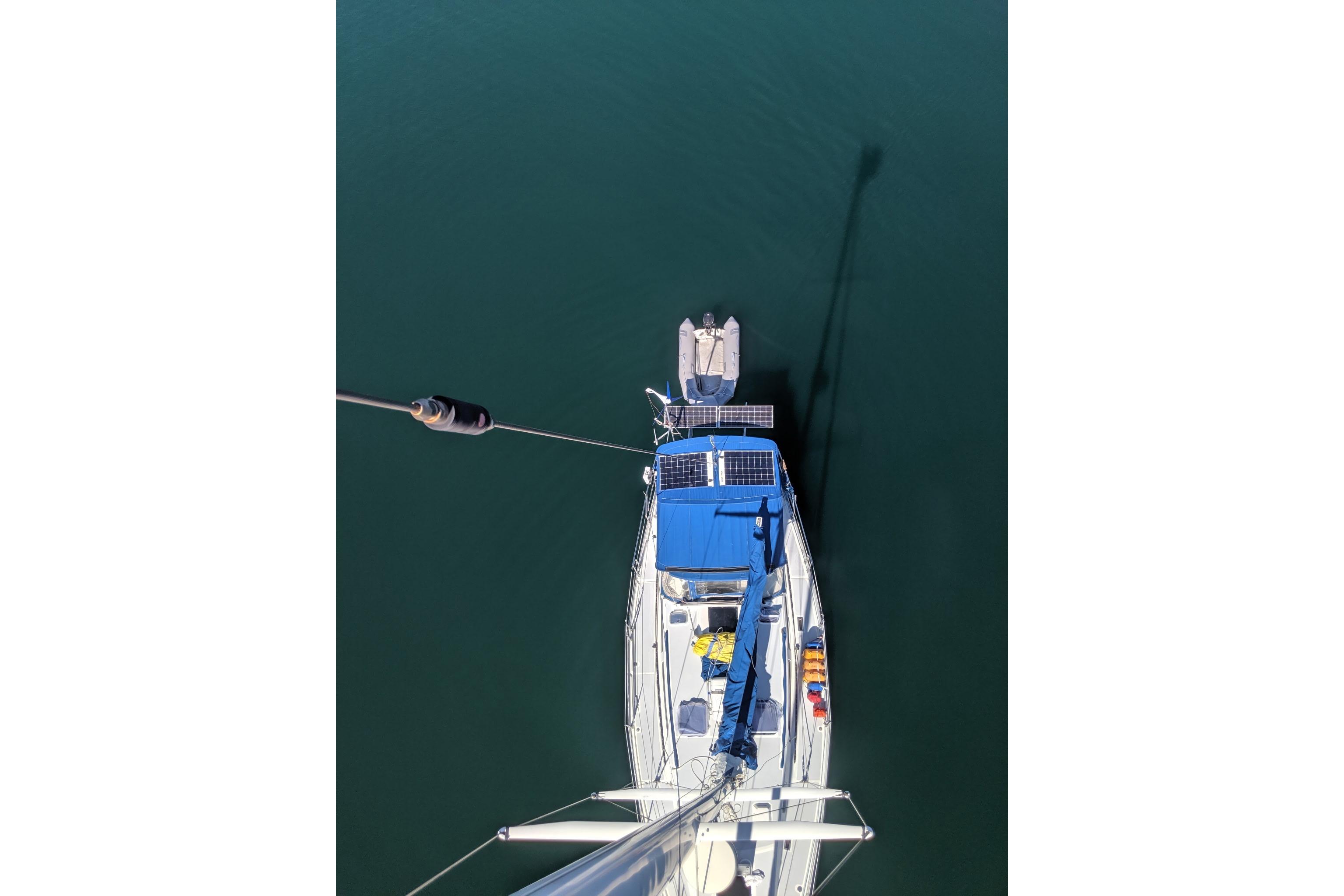 Aerial view of 1987 Norseman 400 sailboat with solar panels and dinghy on calm water.