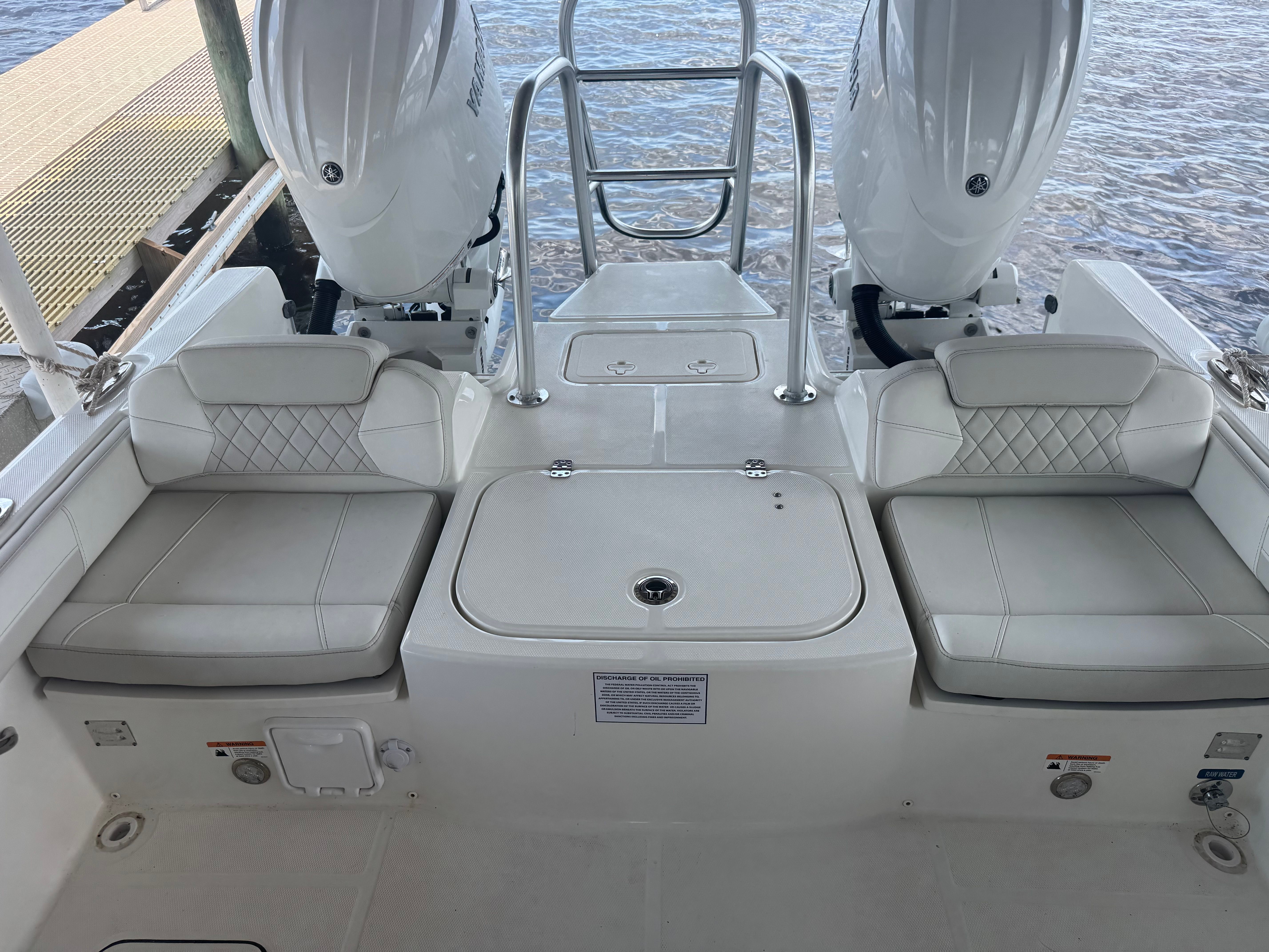 The image shows the stern of a World Cat 230 DC boat with two engines and cushioned seats.