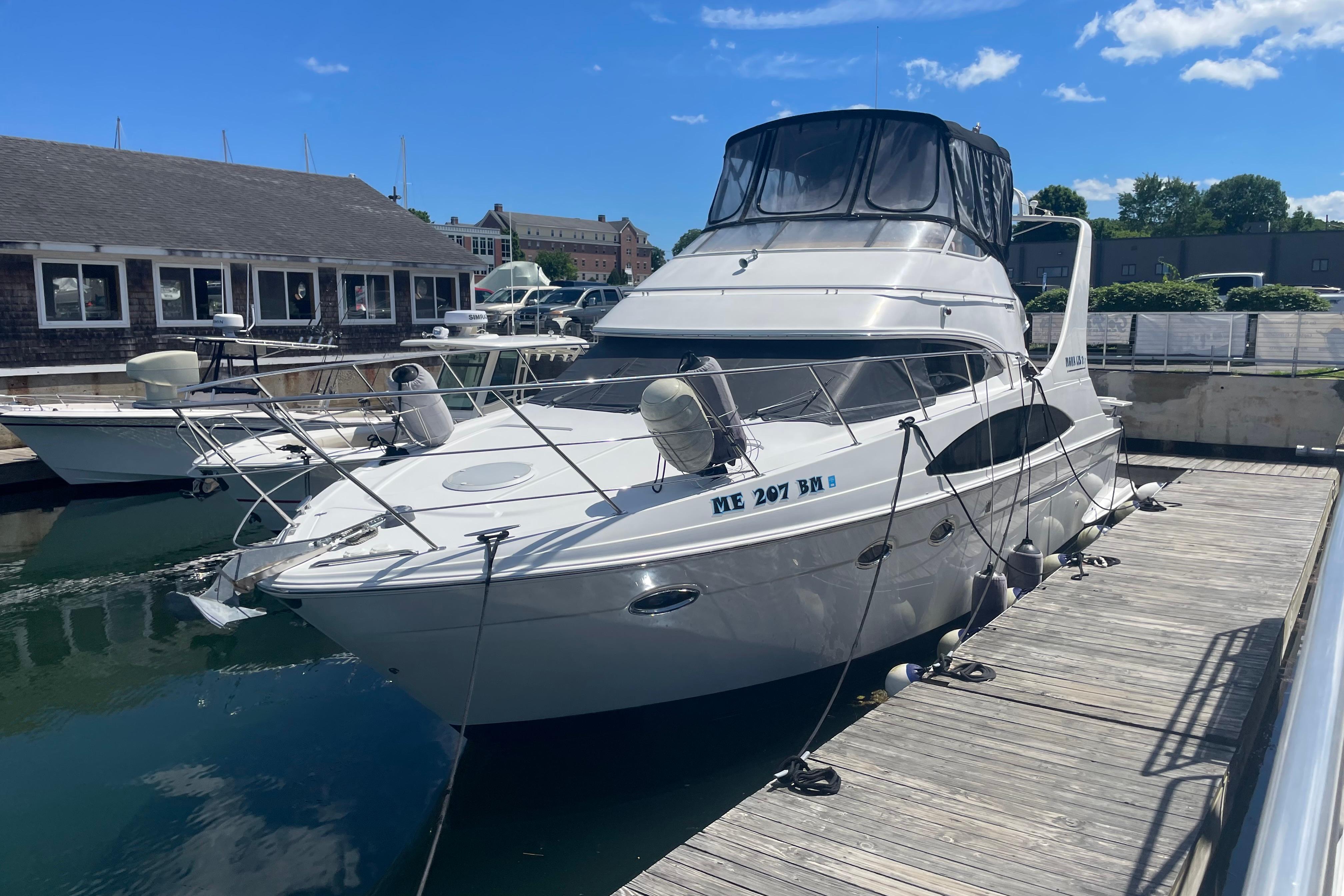 2002 Carver 410 Sport Sedan yacht docked at marina under clear blue sky.