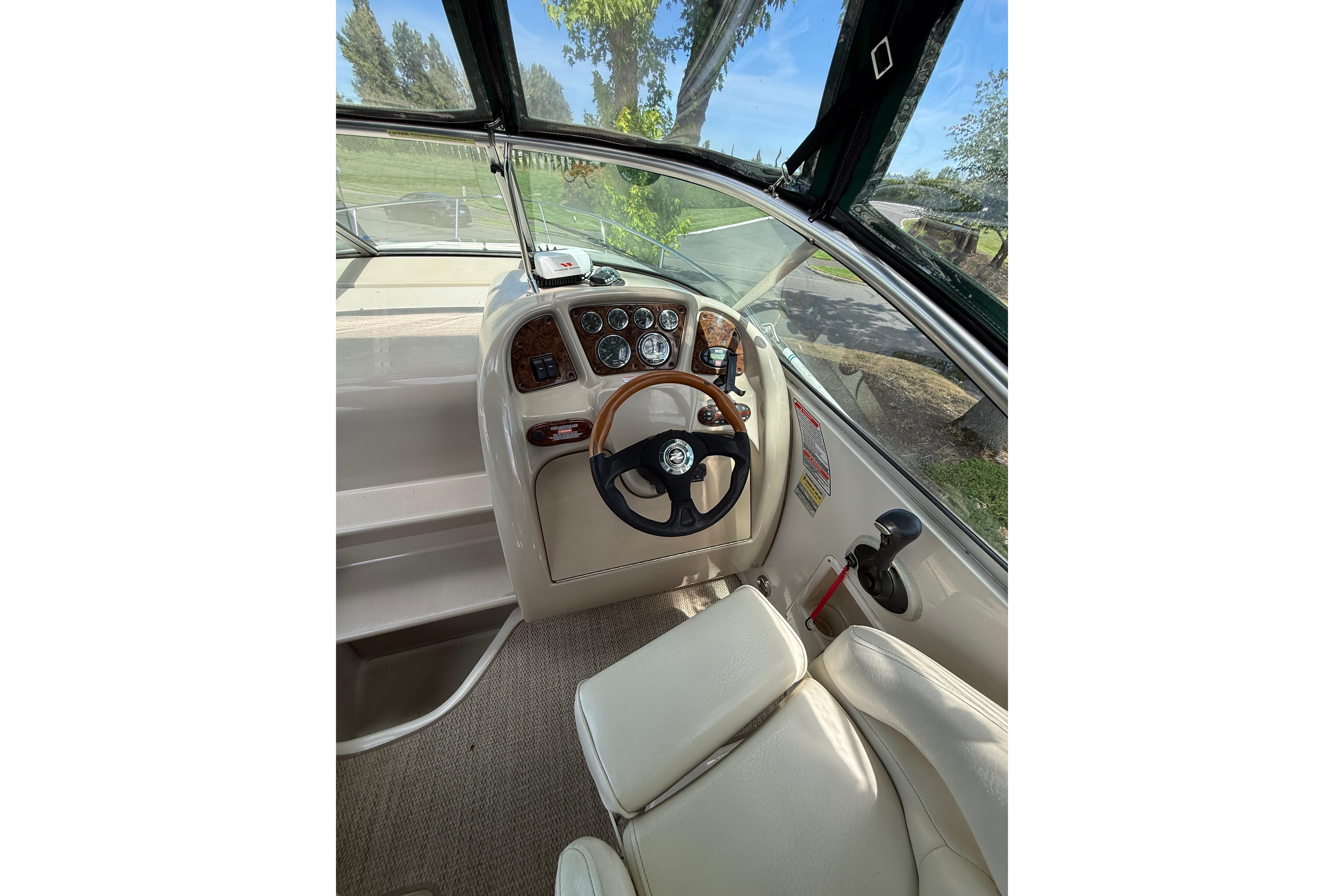 Interior view of 2004 Sea Ray 240 Sundancer boat cockpit with steering wheel and controls.