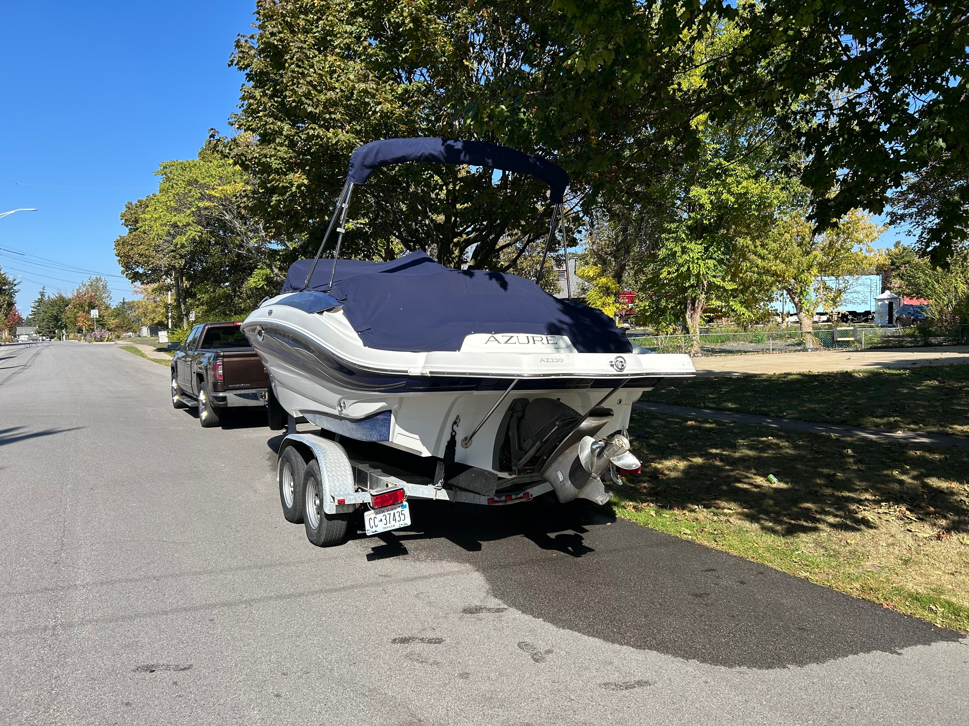 A 2008 Azure AZ220 boat on a trailer, towed by a pickup truck on a street.