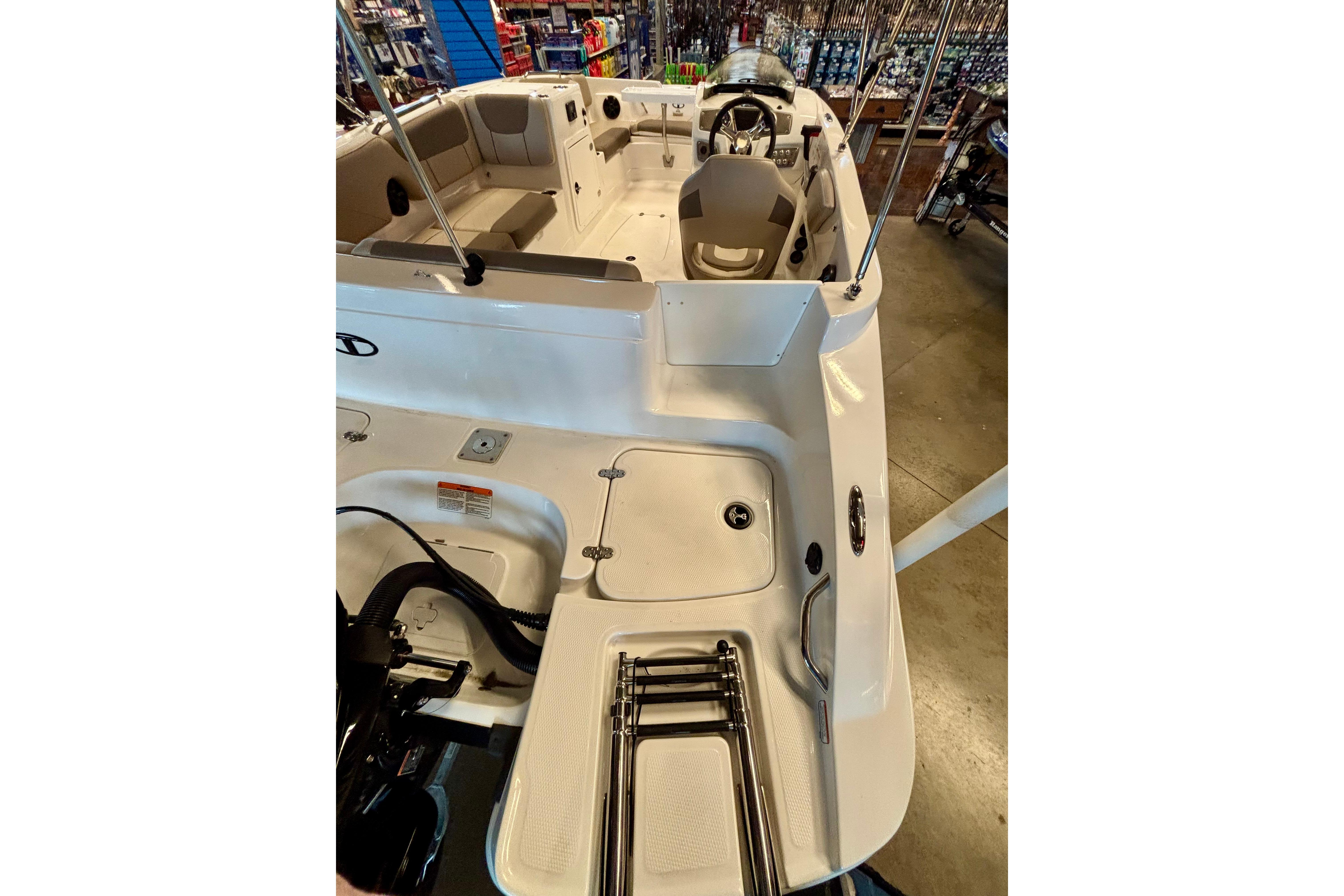 2026 Tahoe 2150 boat interior with seating and steering wheel, displayed in a showroom.