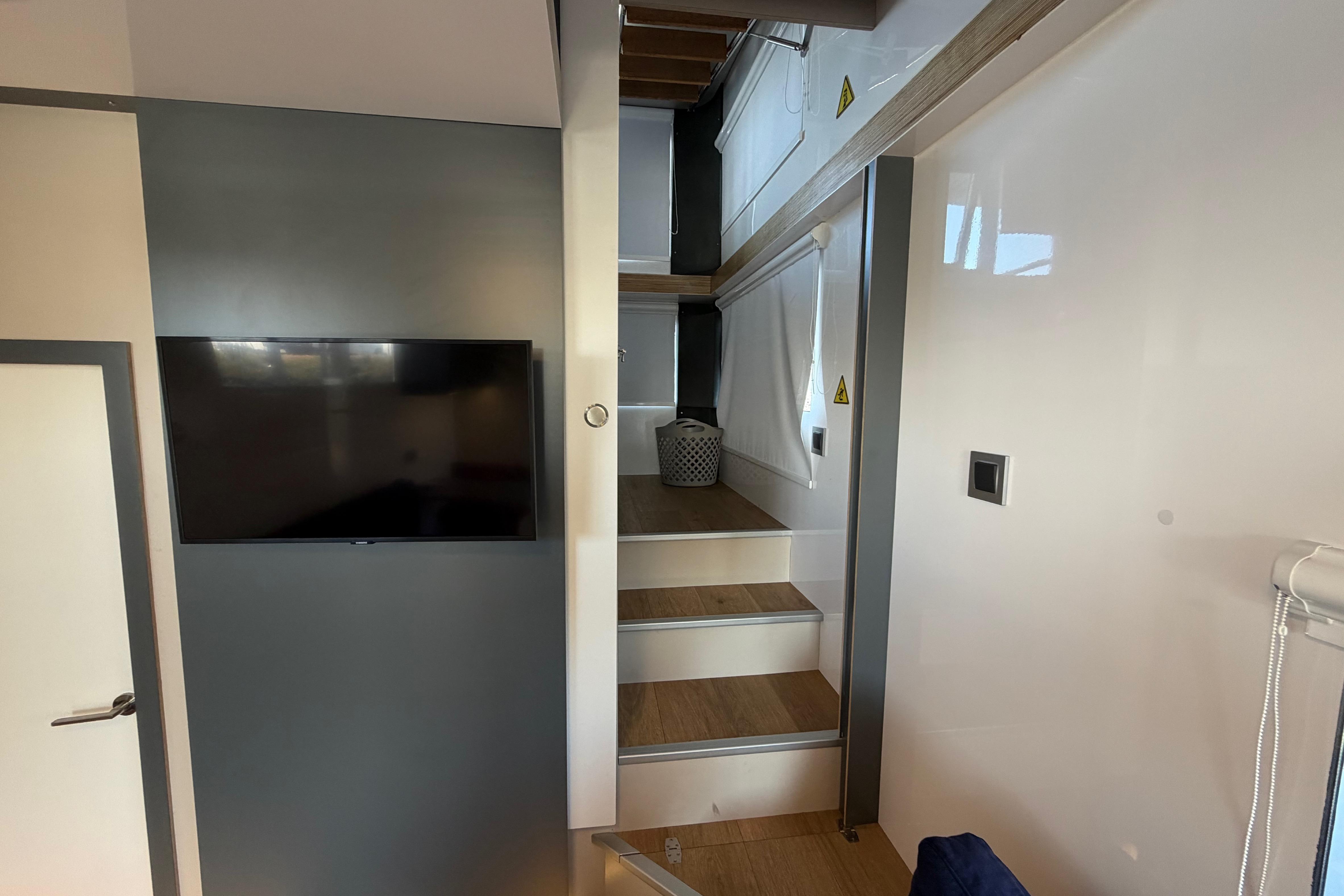 Modern interior of 2022 Navisyo NV.08 with sleek staircase and wall-mounted TV.