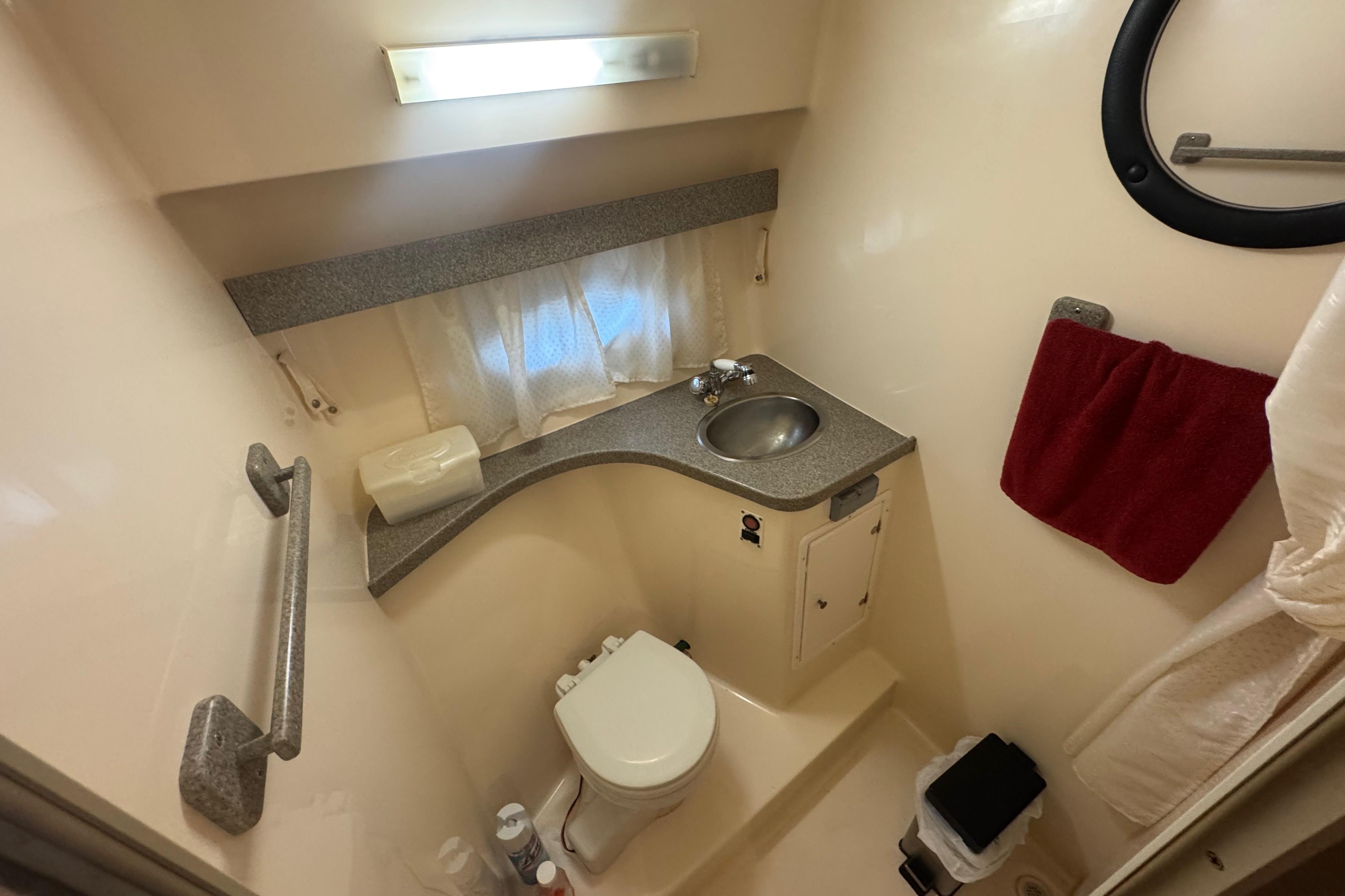 2004 Rinker Fiesta Vee 312 boat bathroom with sink, toilet, and red towel.