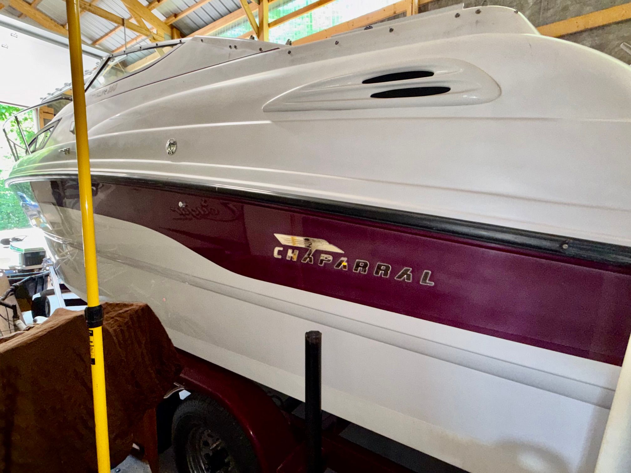 A 1997 Chaparral Signature 260 boat is on a trailer in a covered area.