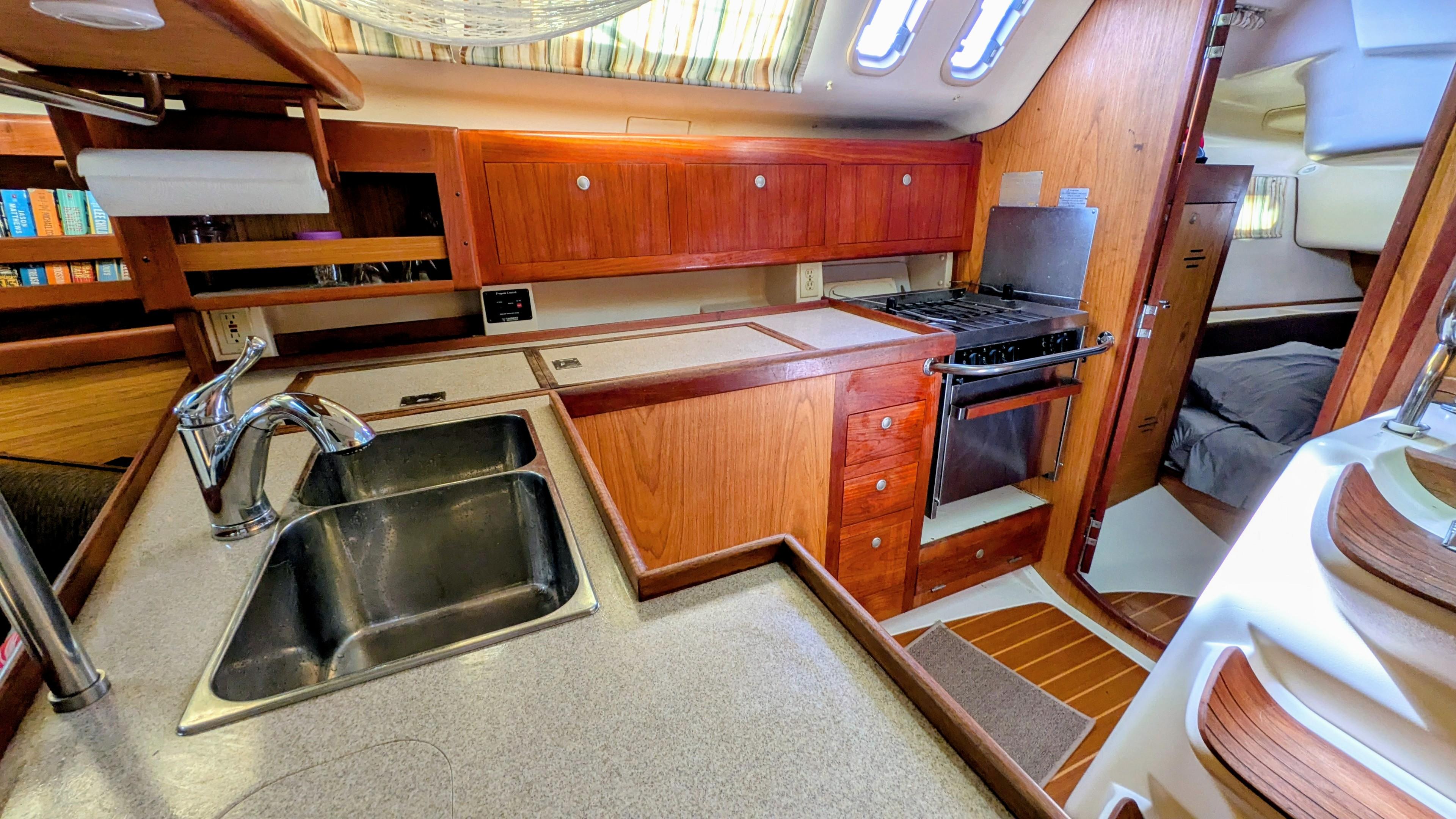 Interior of a 2001 Hunter 380 yacht kitchen with wooden cabinets and stainless steel sink.