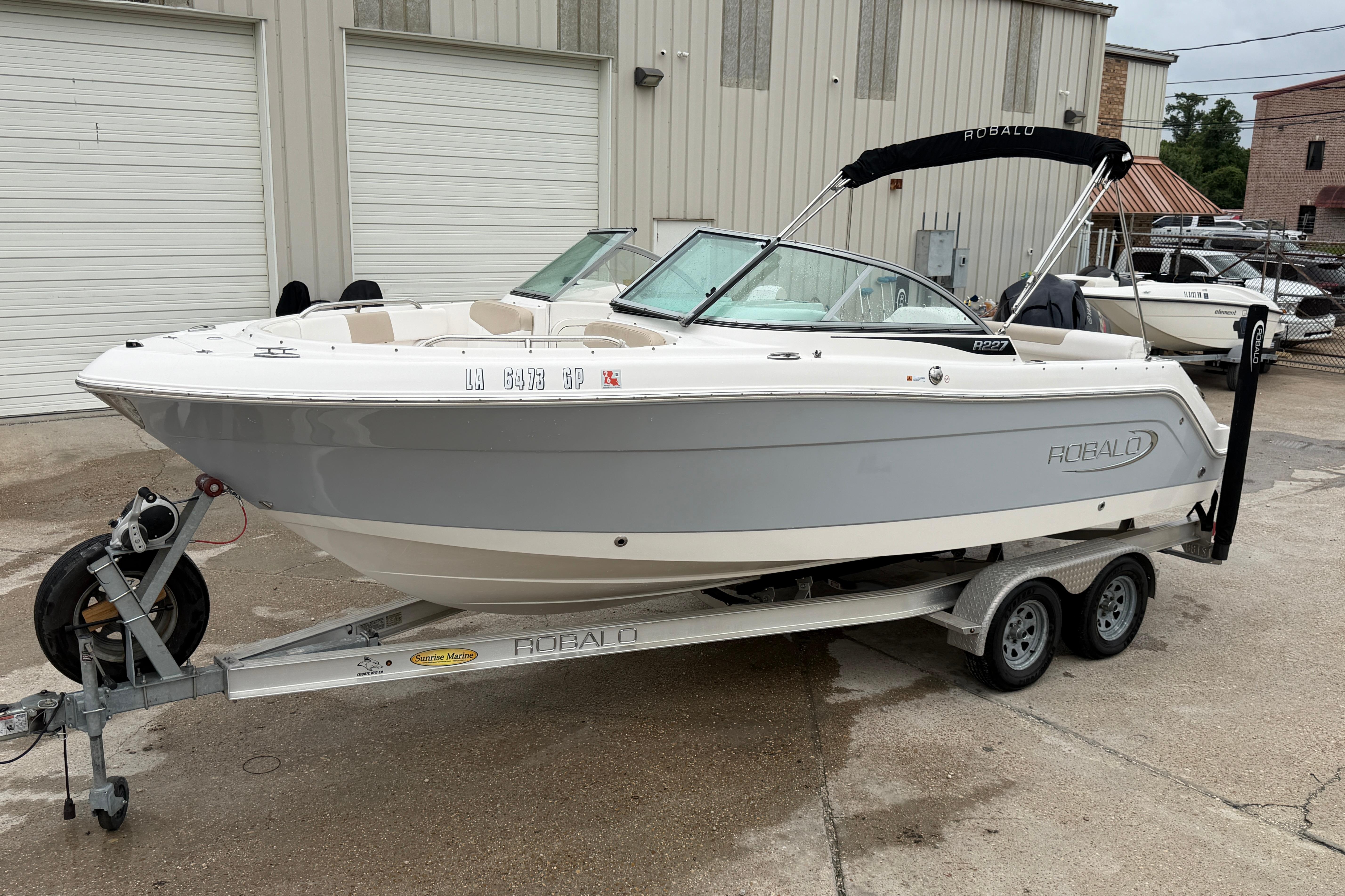 2020 Robalo R227 Dual Console boat on trailer, parked outside a warehouse.
