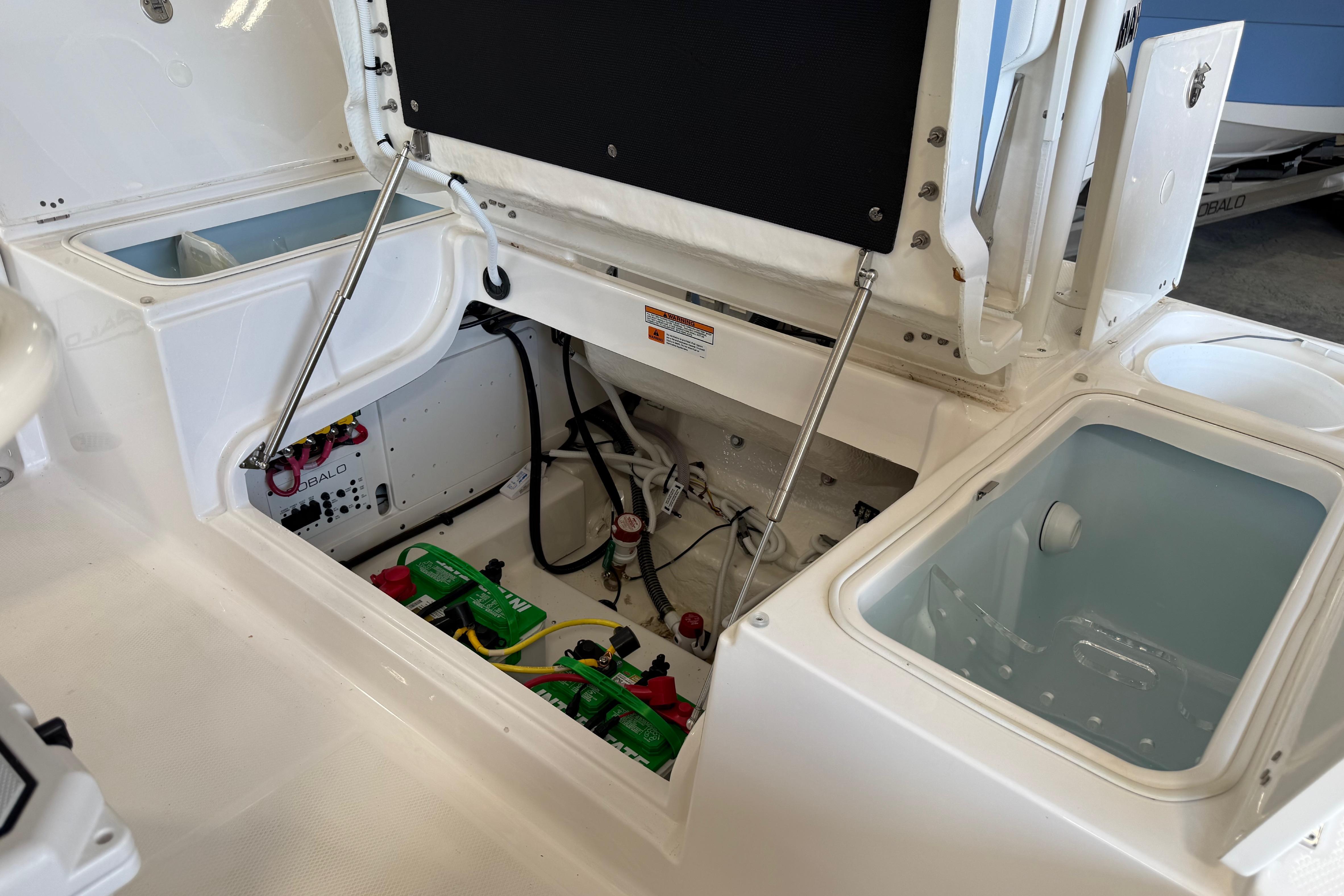 Interior view of 2026 Robalo 246 Cayman boat showing storage and battery compartments.