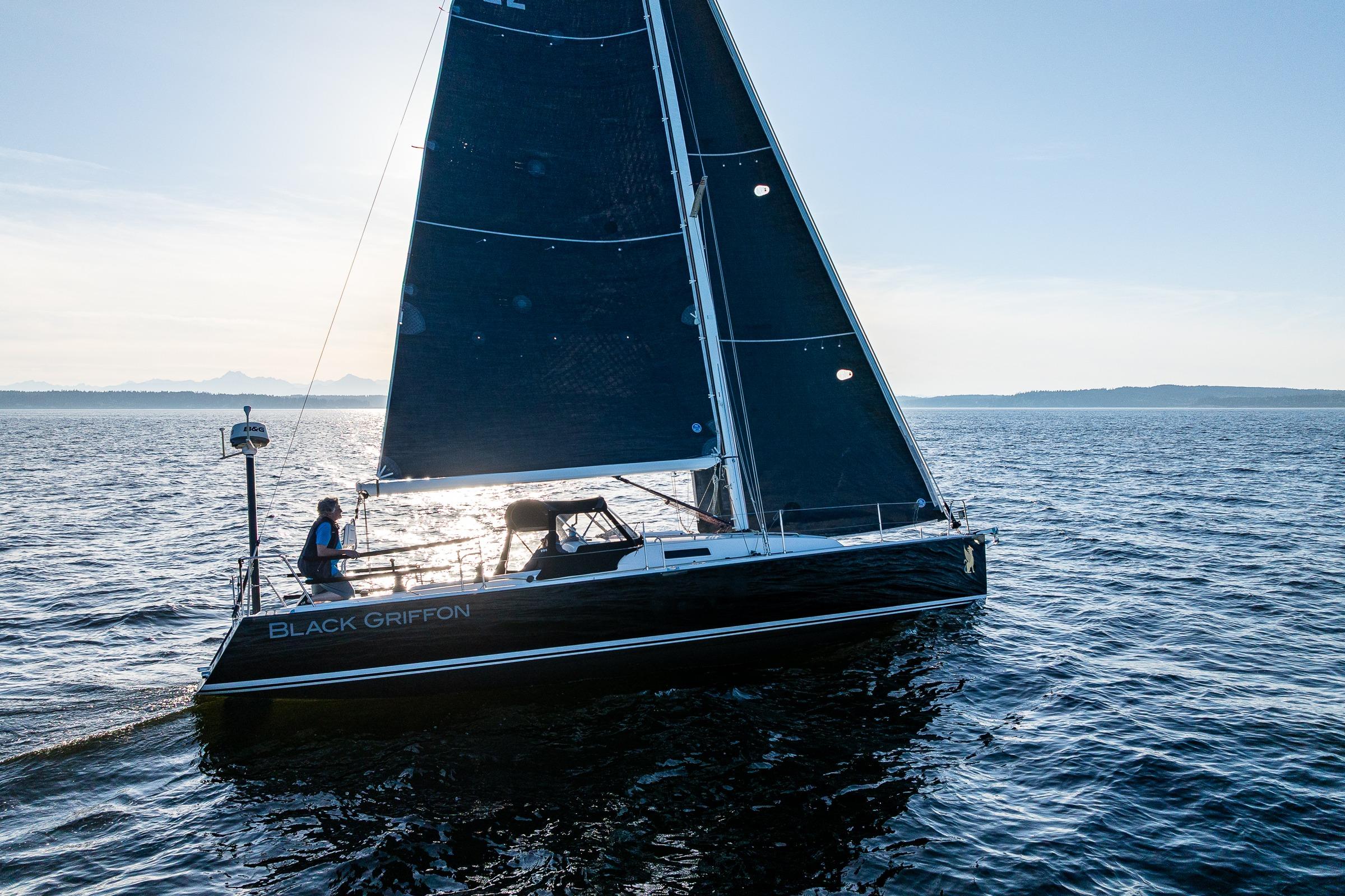 2007 J Boats J/124 sailboat "Black Griffon" sailing on open water at sunset.
