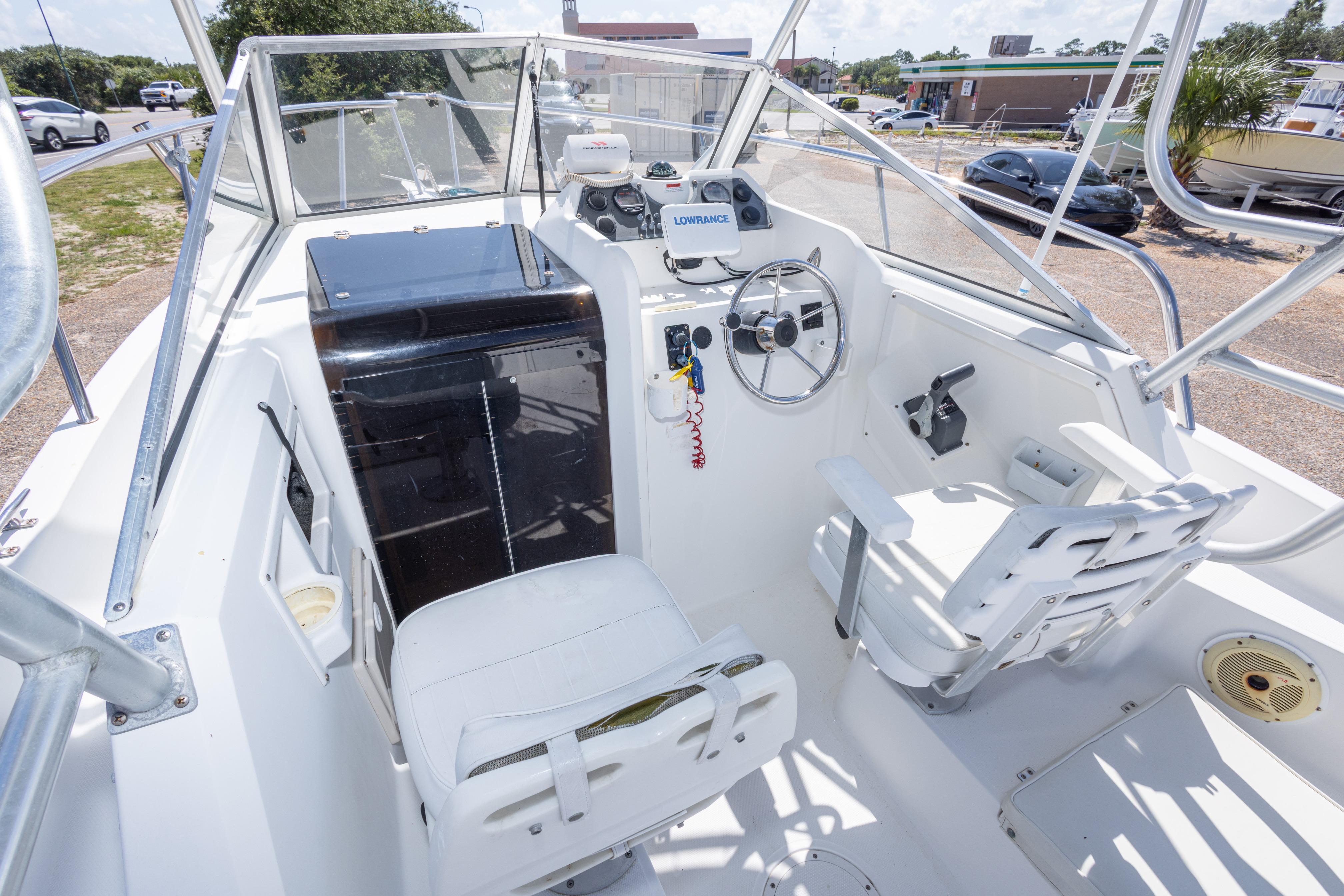 1999 Aquasport 225 Explorer boat cockpit with steering wheel and seating.