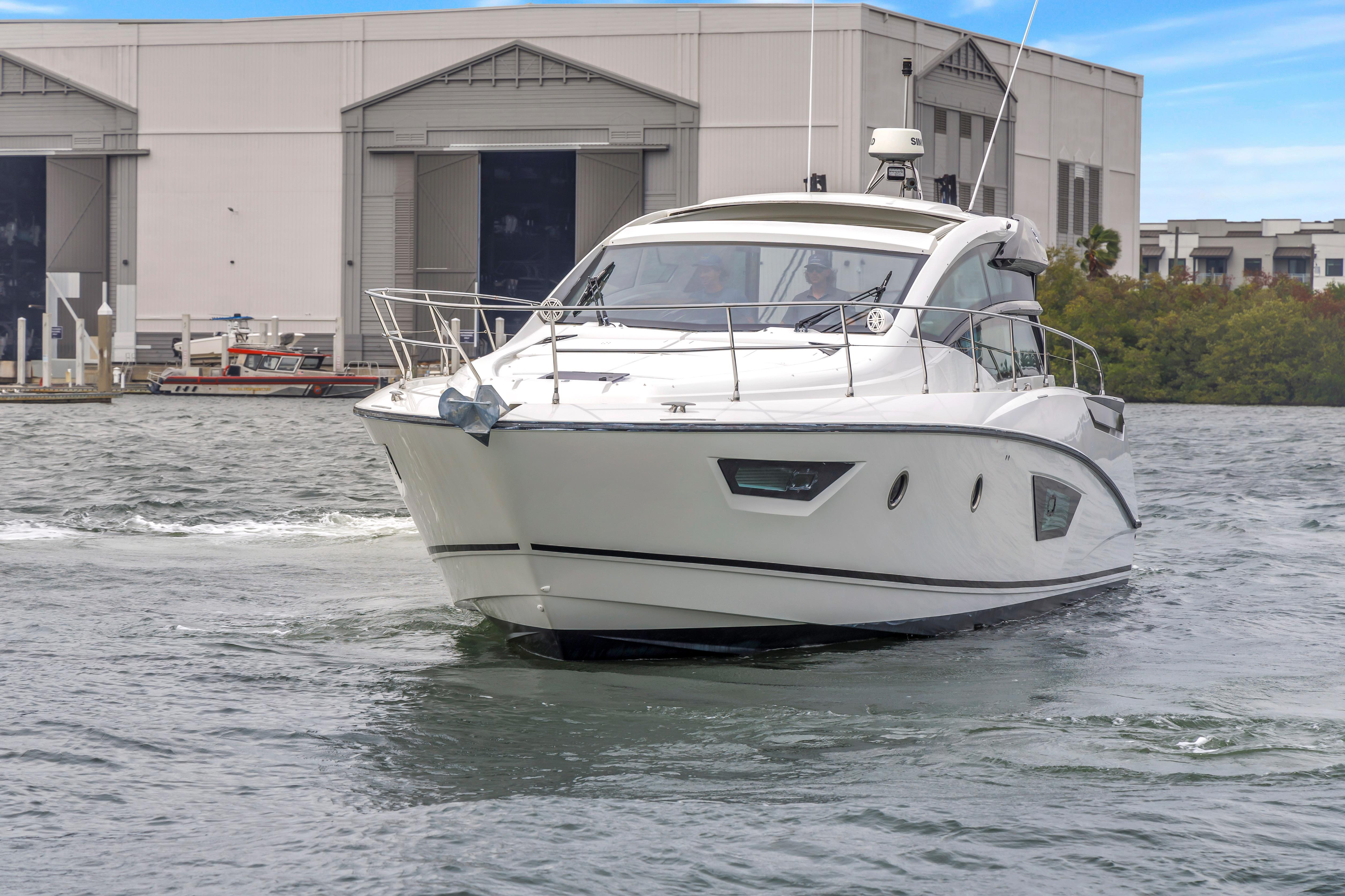 2019 Beneteau Gran Turismo 46 yacht cruising near a marina, showcasing sleek design and elegance.