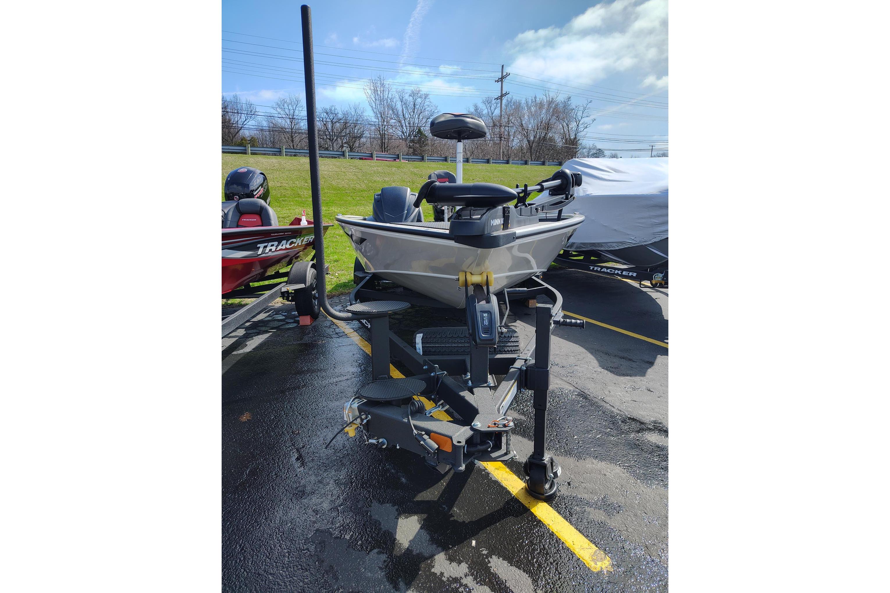 2025 Tracker Savage 215 boat on trailer, parked outdoors under a partly cloudy sky.
