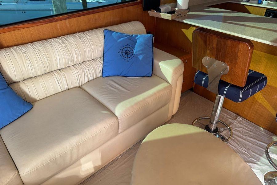 Luxurious interior of 2002 Viking 61 Enclosed Bridge with cream sofa and blue cushions.