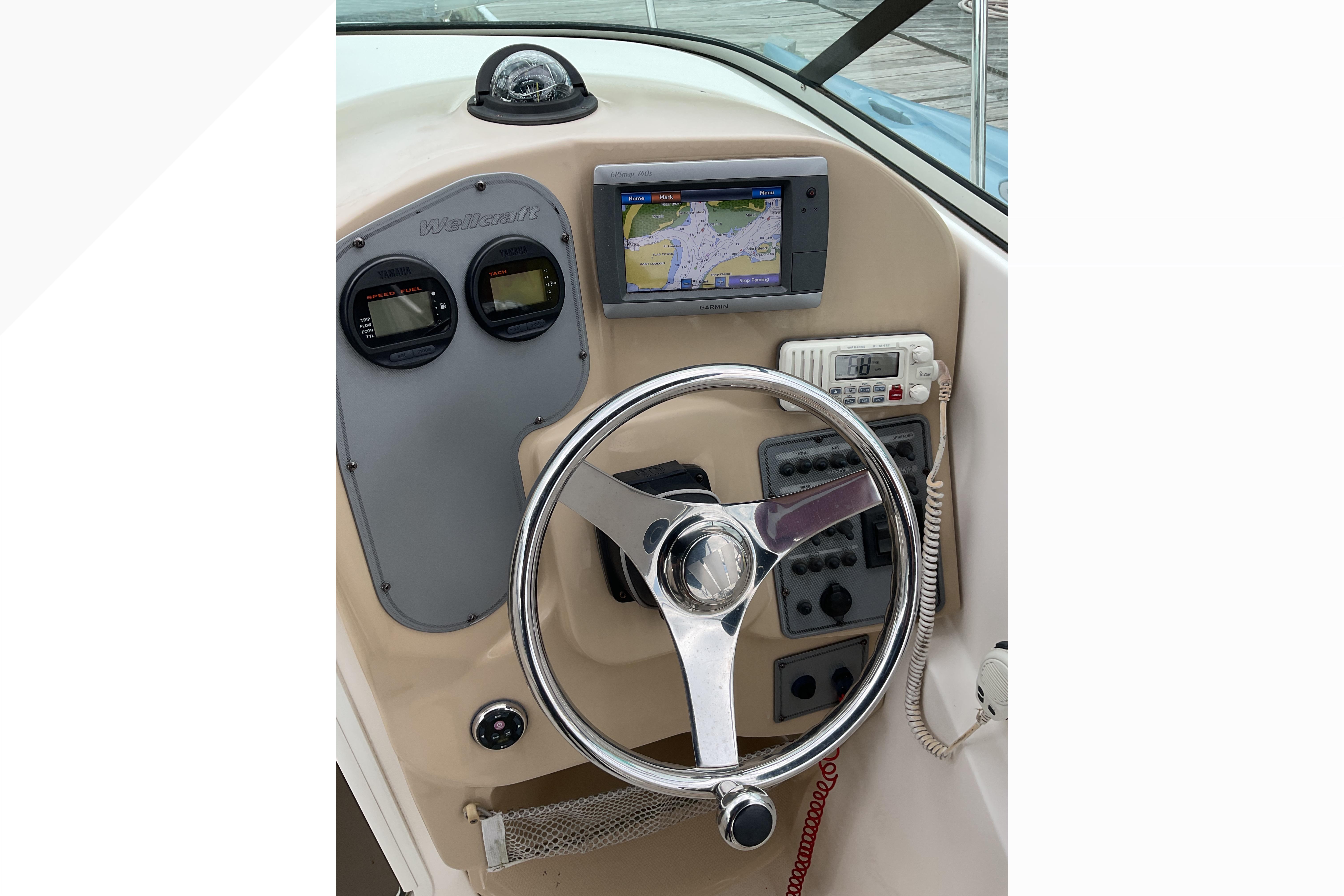 Helm of 2012 Wellcraft 232 Coastal boat with GPS, gauges, and steering wheel.