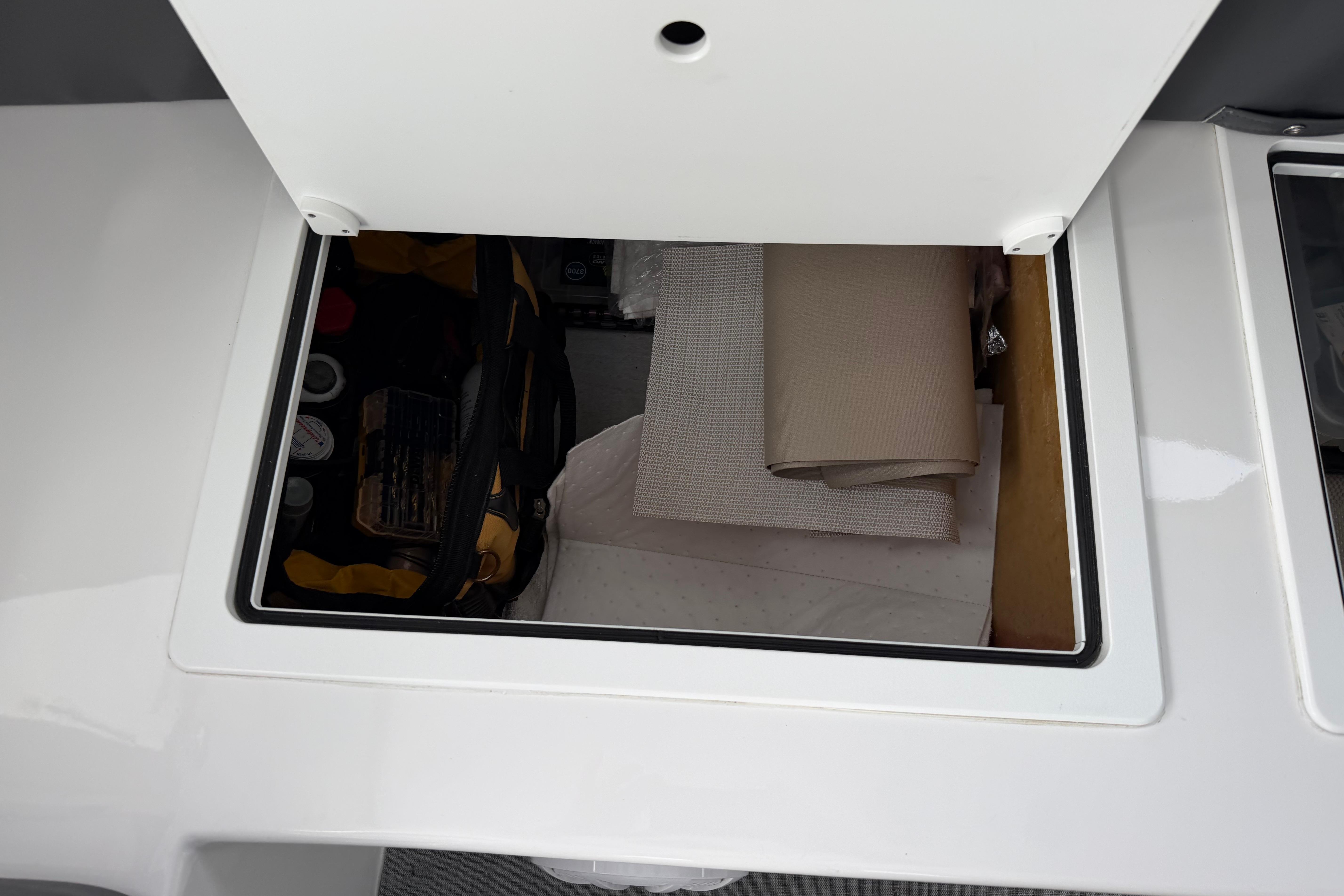 Storage compartment on a 2018 H&H Marine Osmond Beal boat, containing tools and materials.