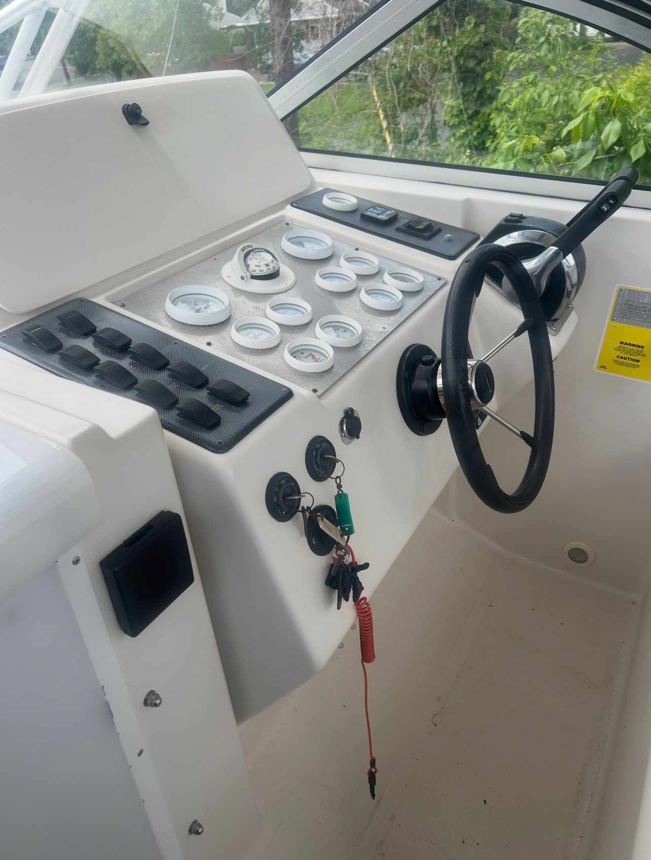 The cockpit of a boat with a steering wheel and instrument panel.