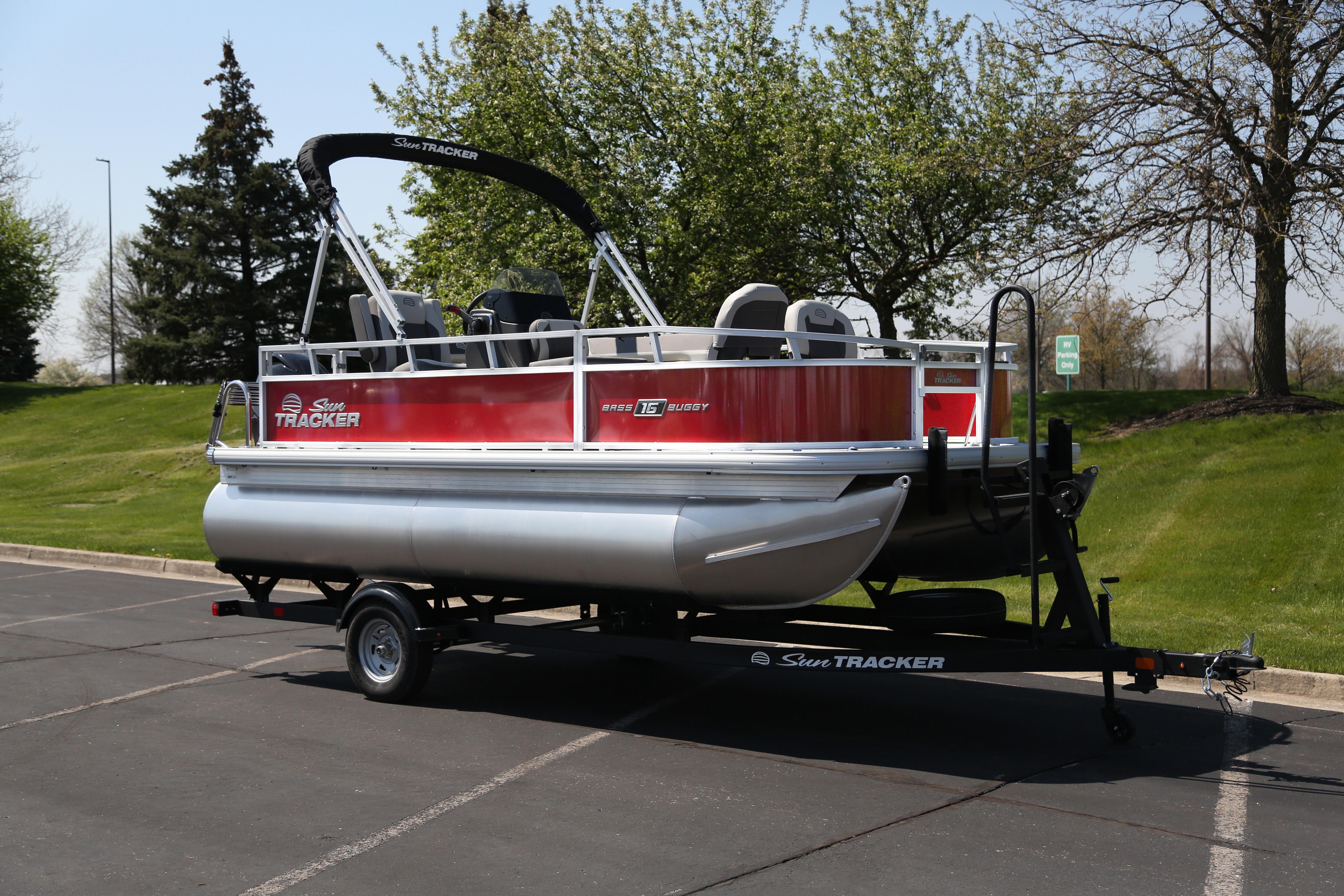2026 Sun Tracker Bass Buggy 16 XL Select pontoon boat on trailer in parking lot.