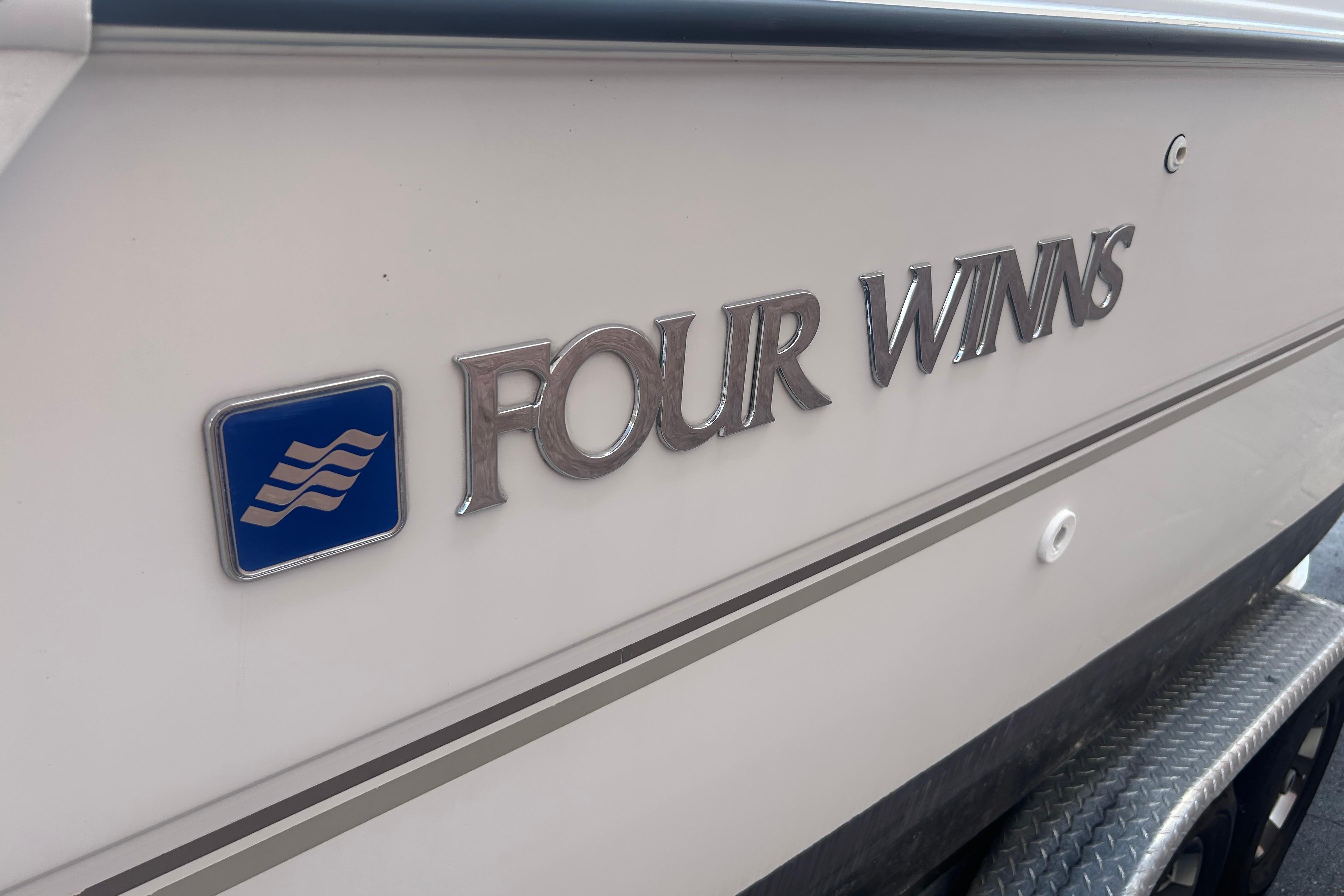 1998 Four Winns 258 Vista boat logo on white hull with blue emblem.