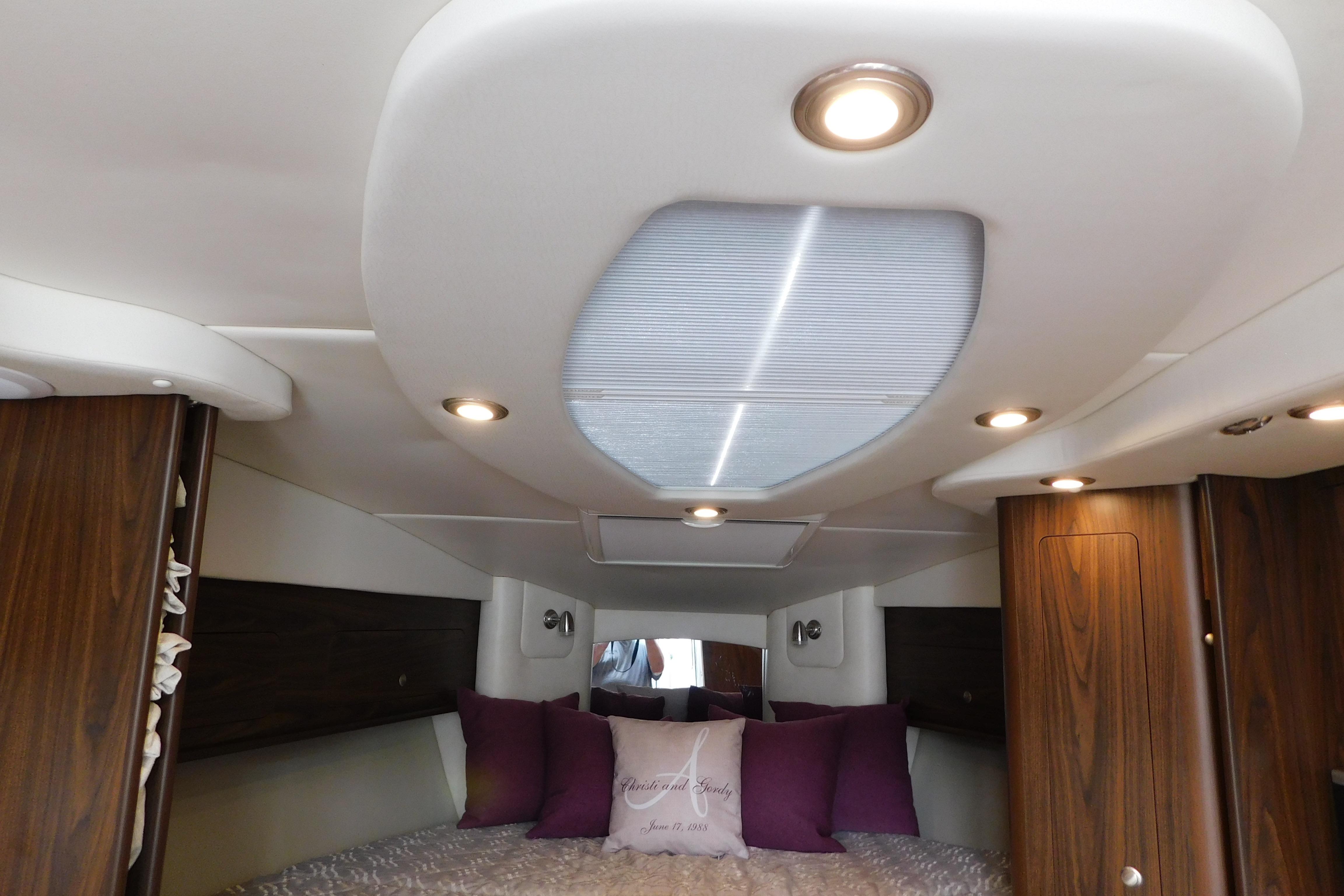 Interior cabin of 2017 Rinker EX 320 boat with cozy bedding and ambient lighting.
