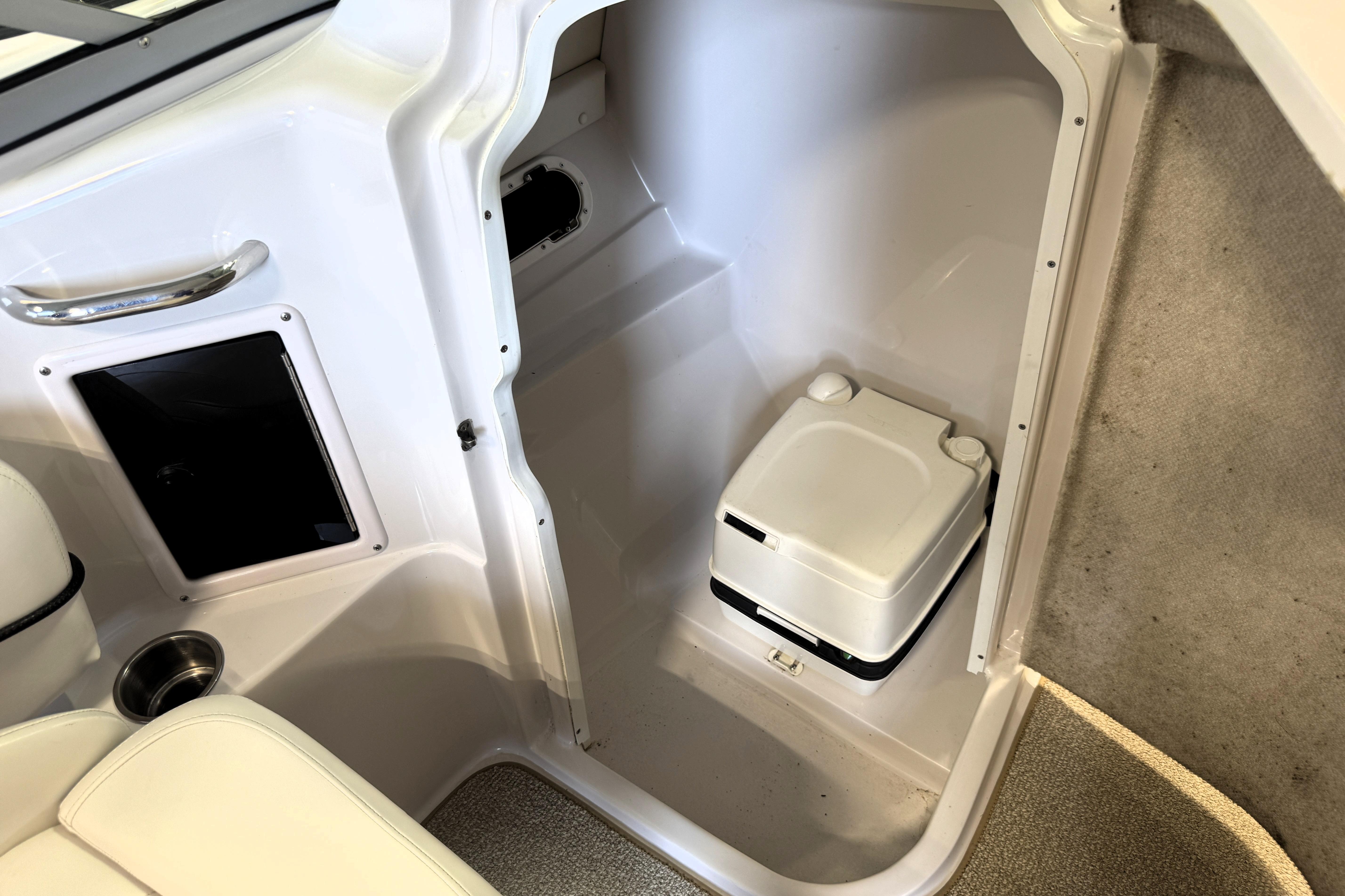 2008 Four Winns H240 boat interior with compact portable toilet and storage compartment.