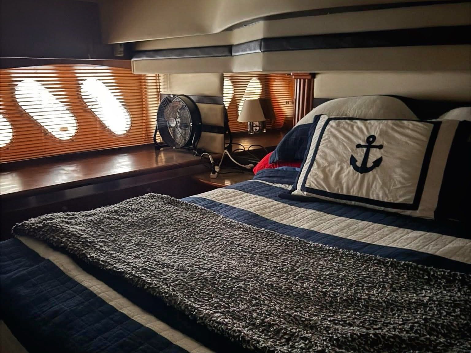 Cozy cabin with a bed, striped bedding, and an anchor pillow, surrounded by wood paneling.