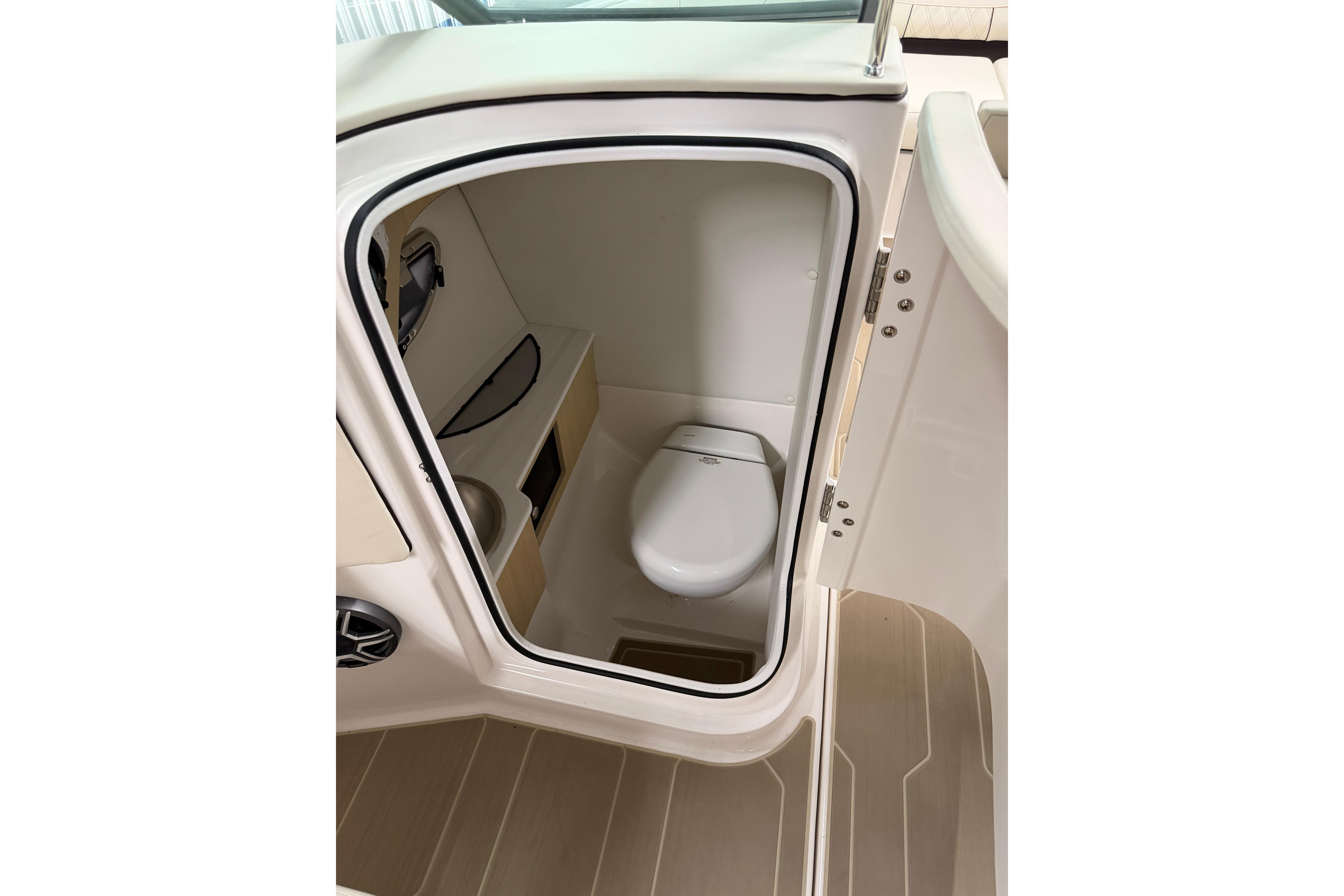 Interior view of 2026 Regal LS6 boat bathroom with compact toilet and storage.