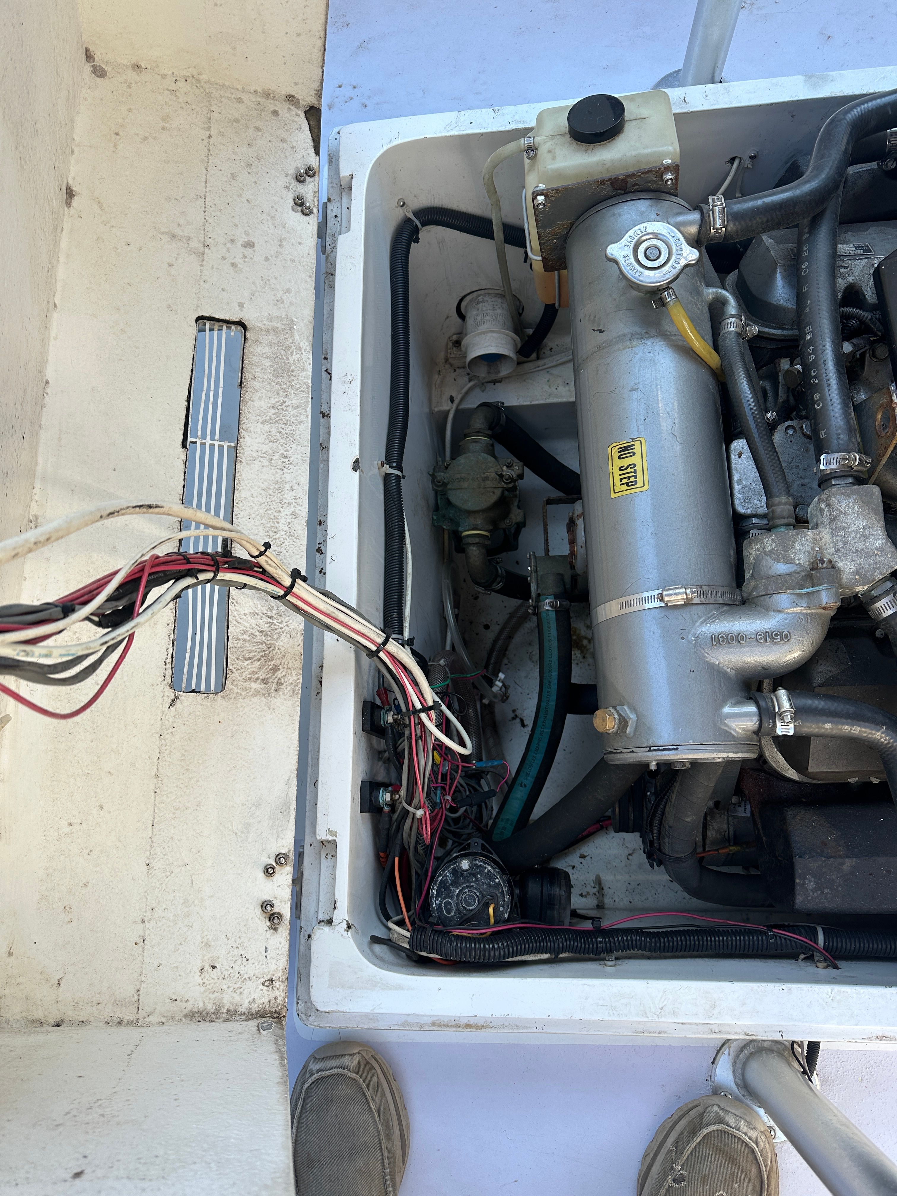 Engine compartment of a 1976 Blackfin Fisherman boat with visible wires and engine.