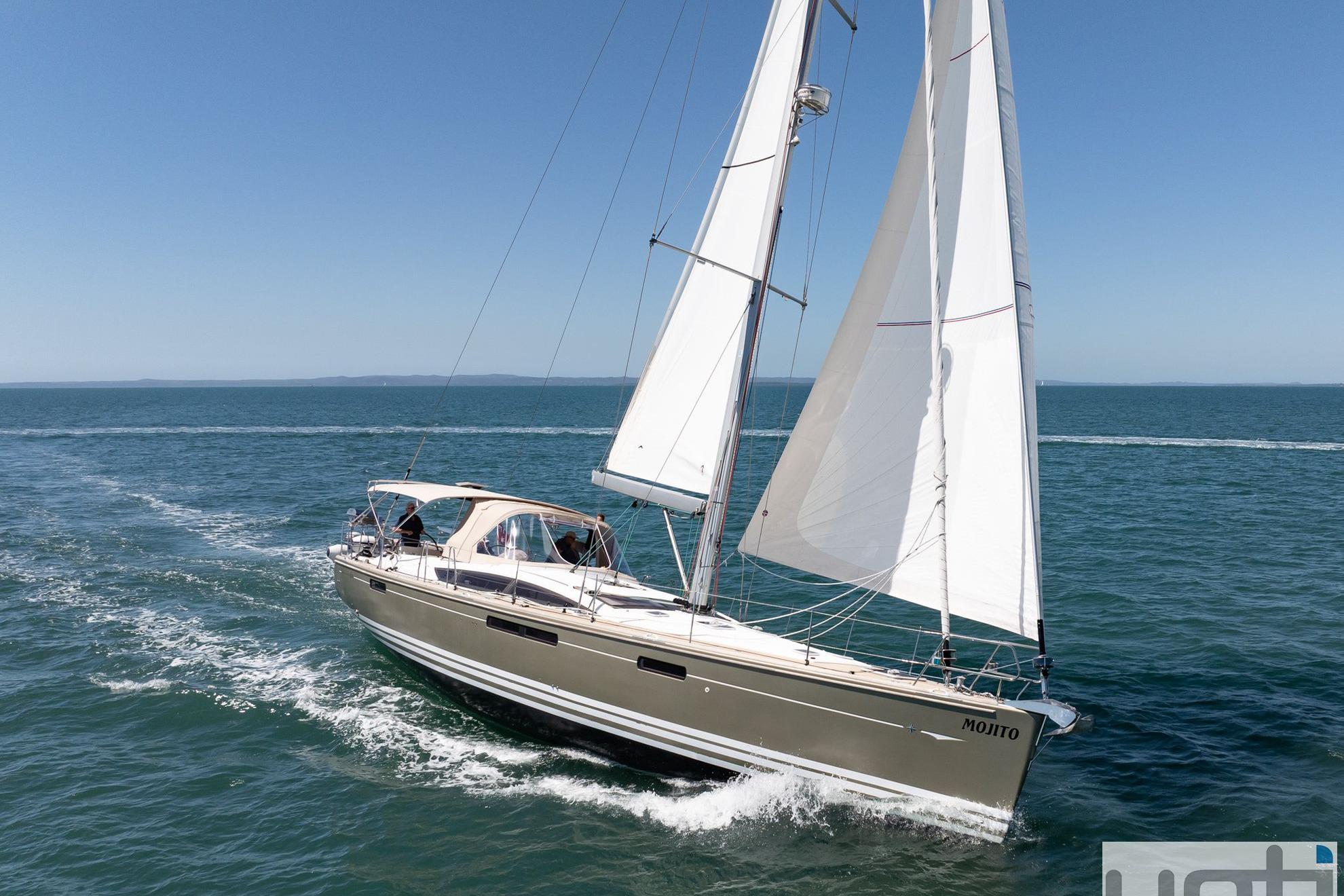 Sailing yacht Jeanneau 57, 2015 model, cruising on open sea under clear blue sky.