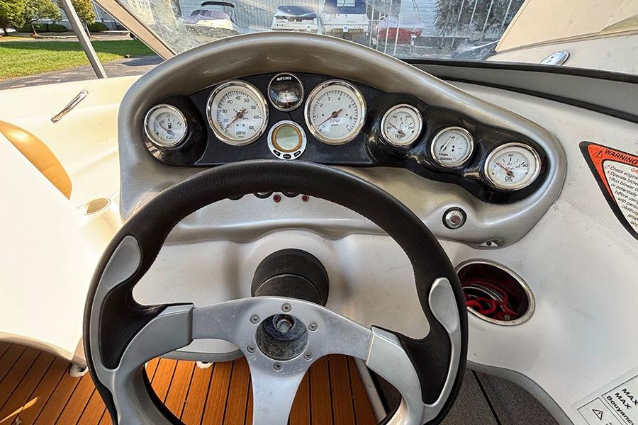Steering wheel and dashboard of a 2009 Tahoe Q5i Sport boat, featuring multiple gauges.