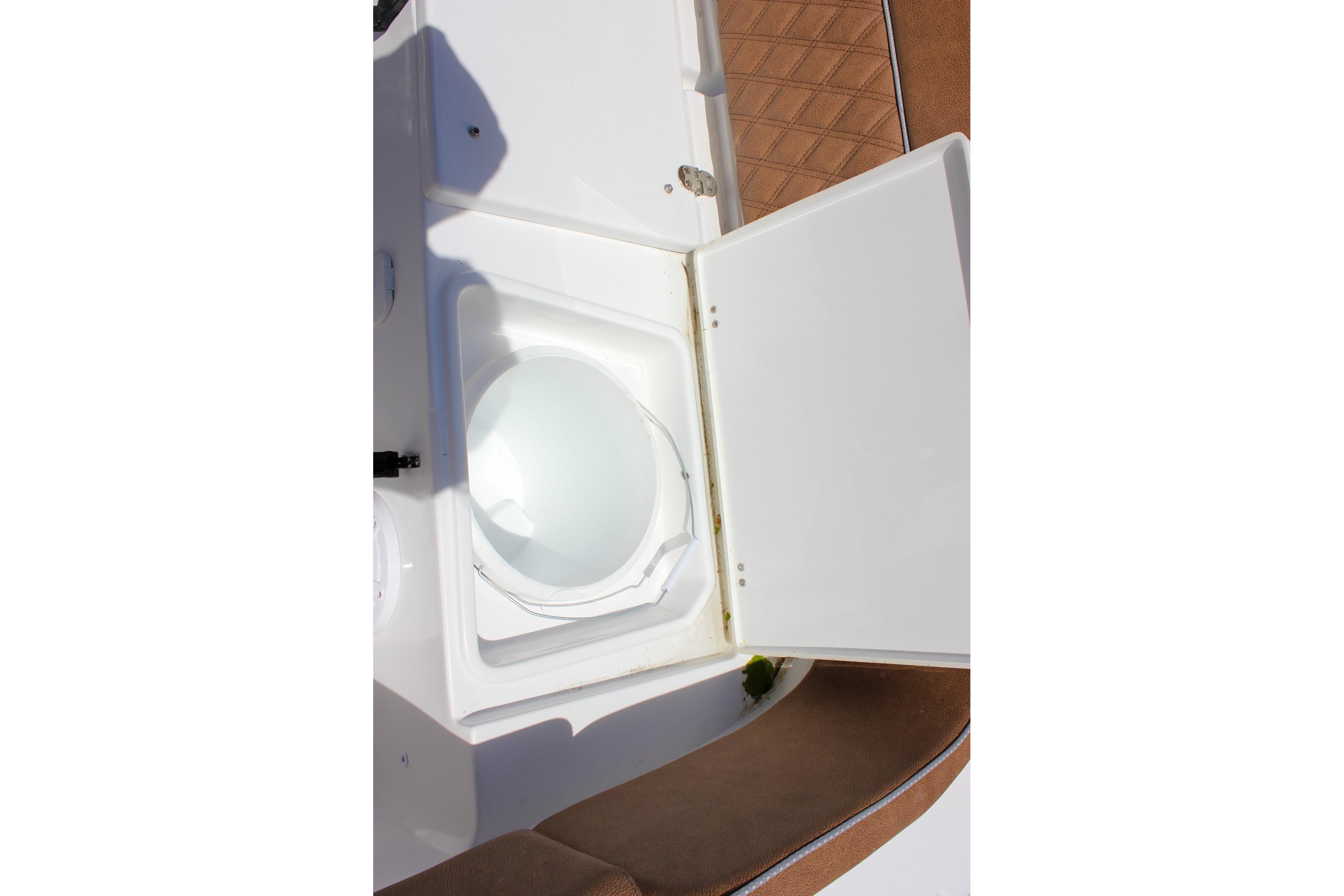 Open storage compartment on 2027 Sea Hunt Ultra 234 boat, featuring white interior and brown seating.