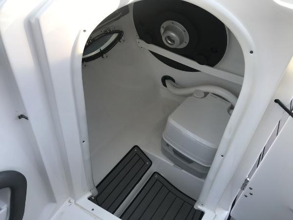 2020 Rinker 29QX BR boat interior with compact toilet and porthole.