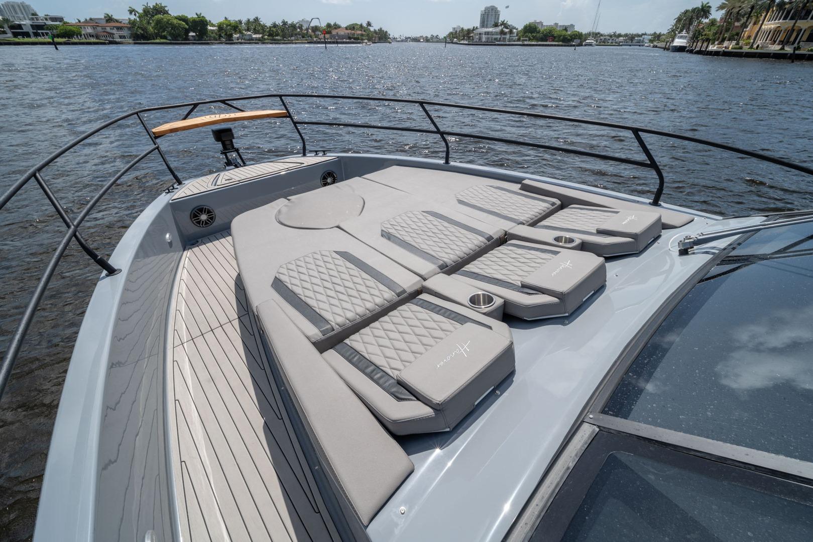 Luxurious 2026 Hanover 387 yacht deck with cushioned sunbathing area on a scenic waterway.