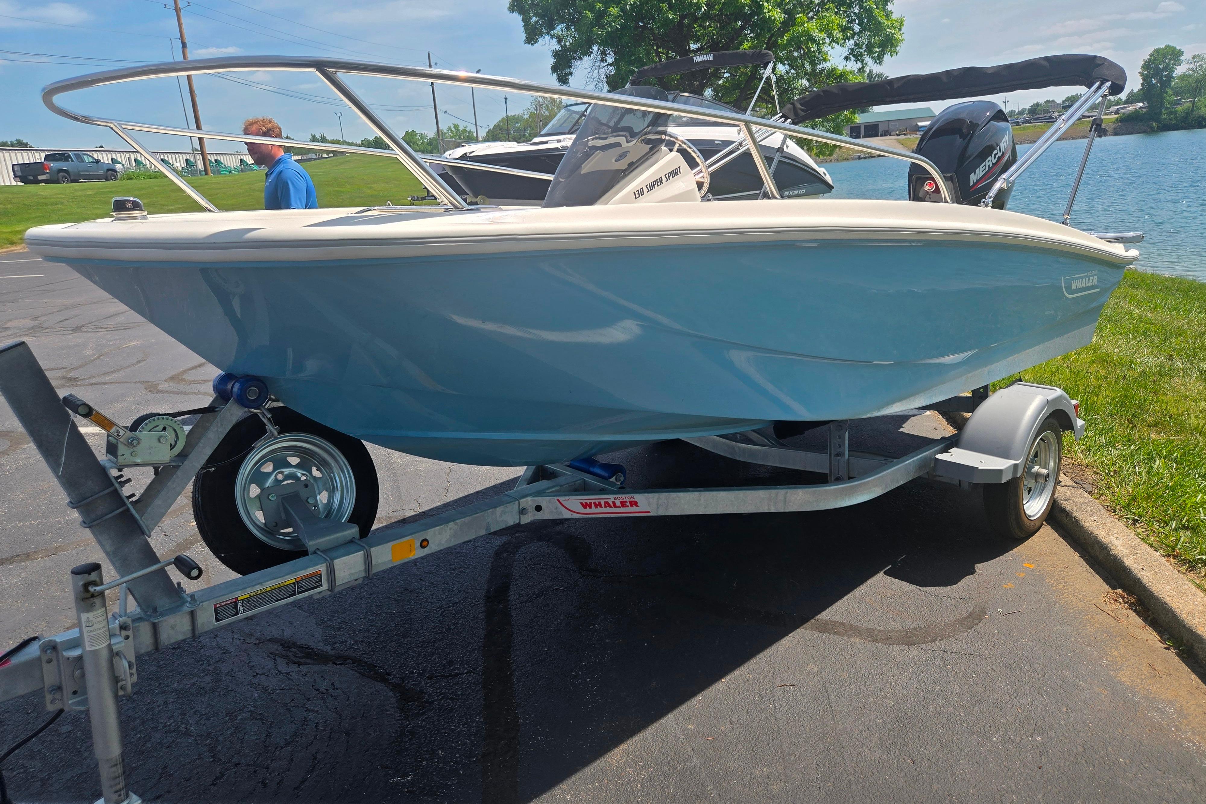 2025 Boston Whaler 130 Super Sport boat on trailer by a lake.