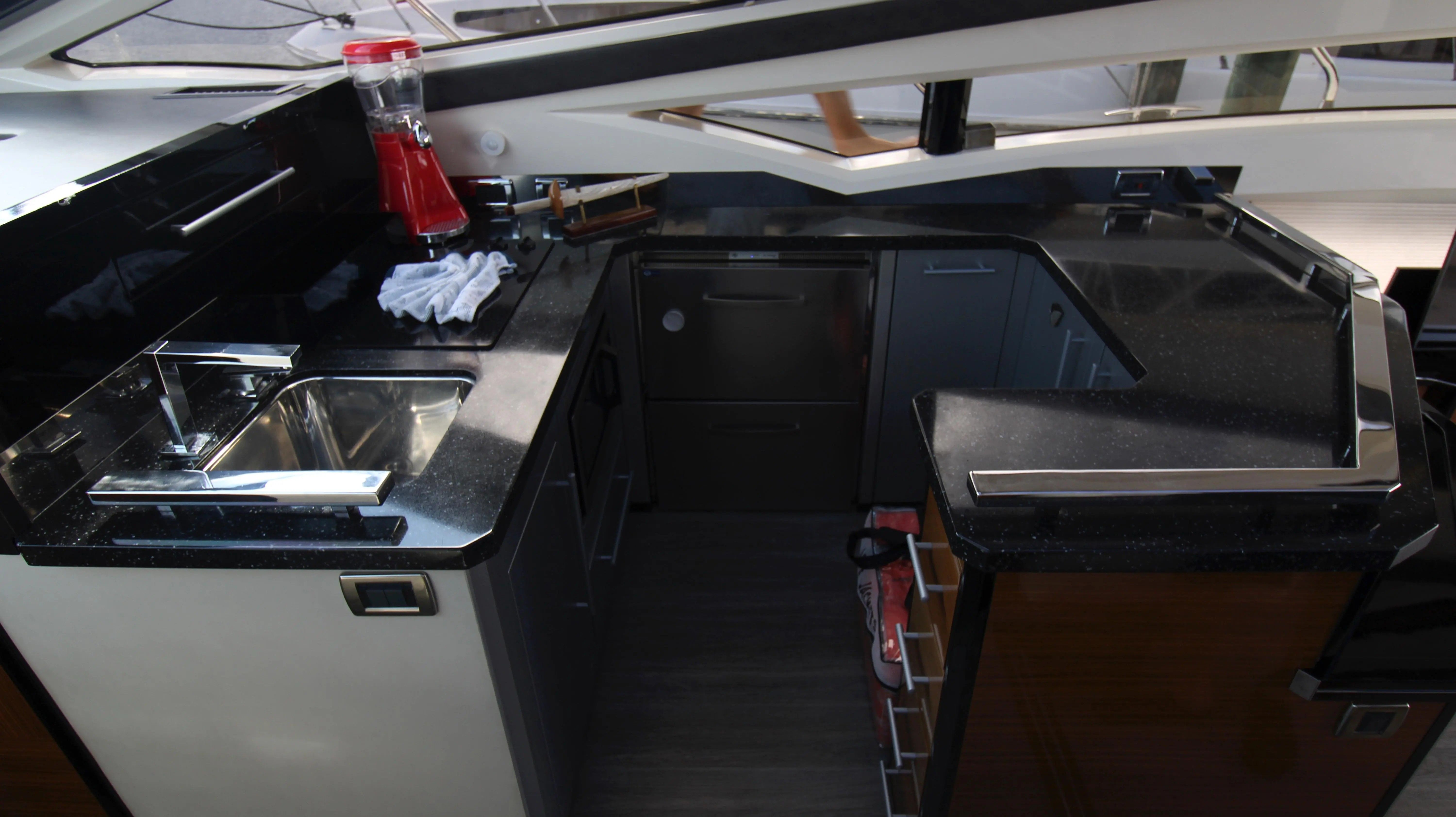 The galley of a 2010 Marquis Sport Coupe with black countertop and stainless steel sink.
