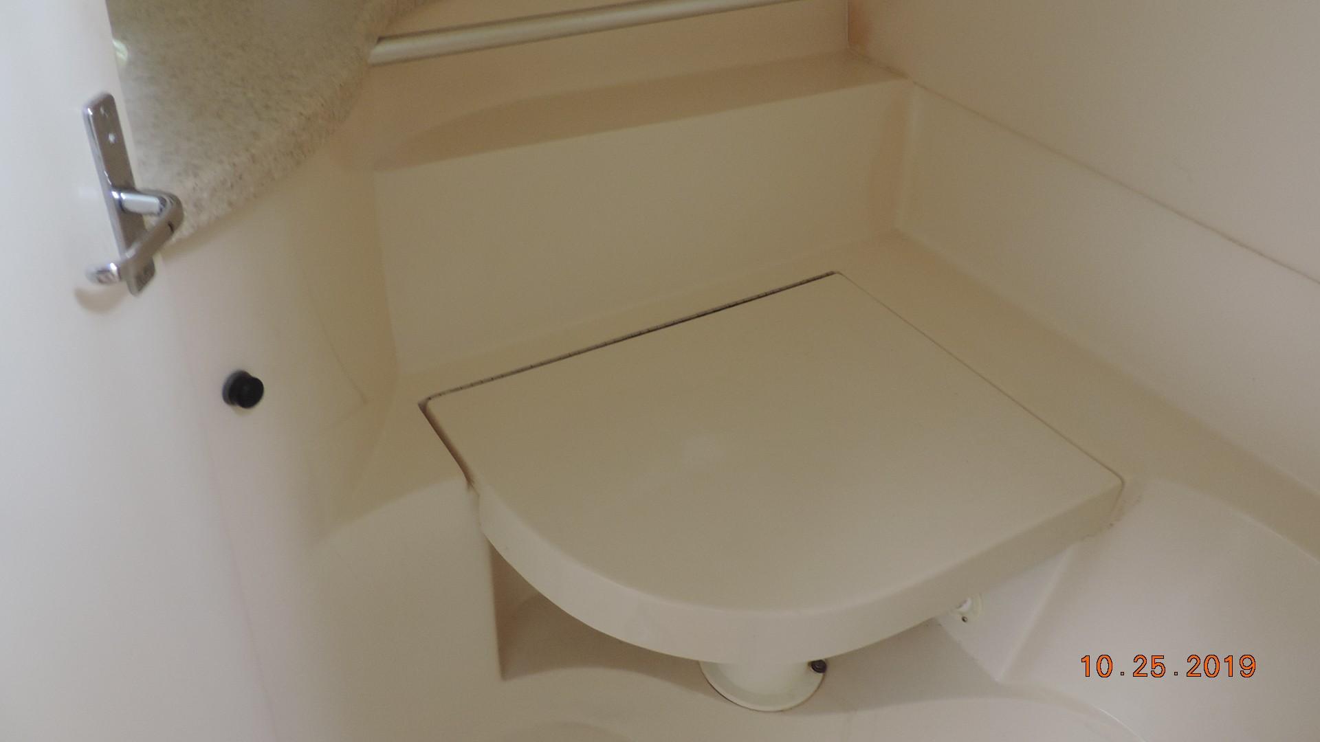 1998 Mainship 30 PILOT boat interior with a compact, foldable seat in a beige finish.