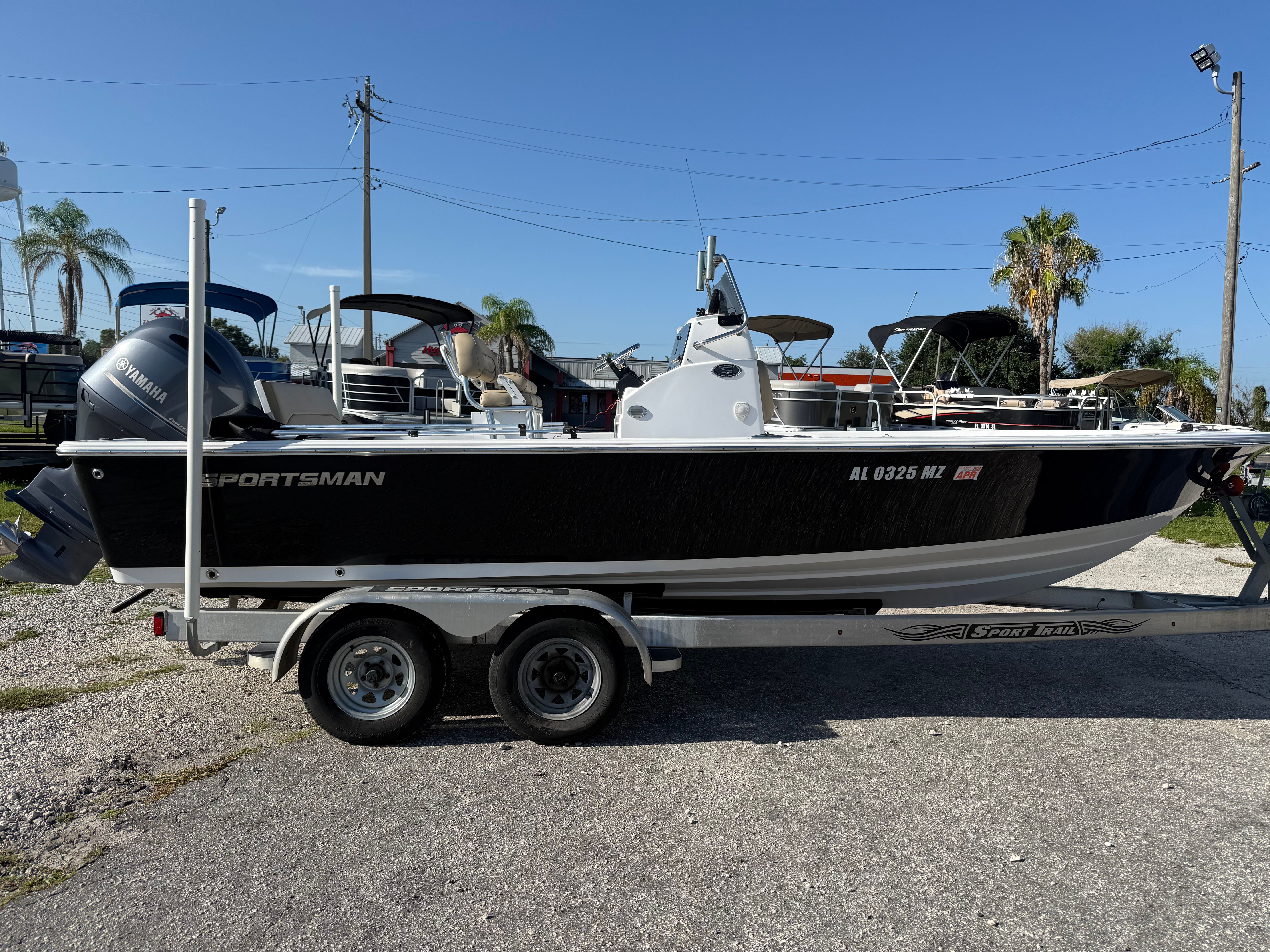 A 2016 Sportsman Masters 227 Bay Boat on a trailer, surrounded by palm trees.