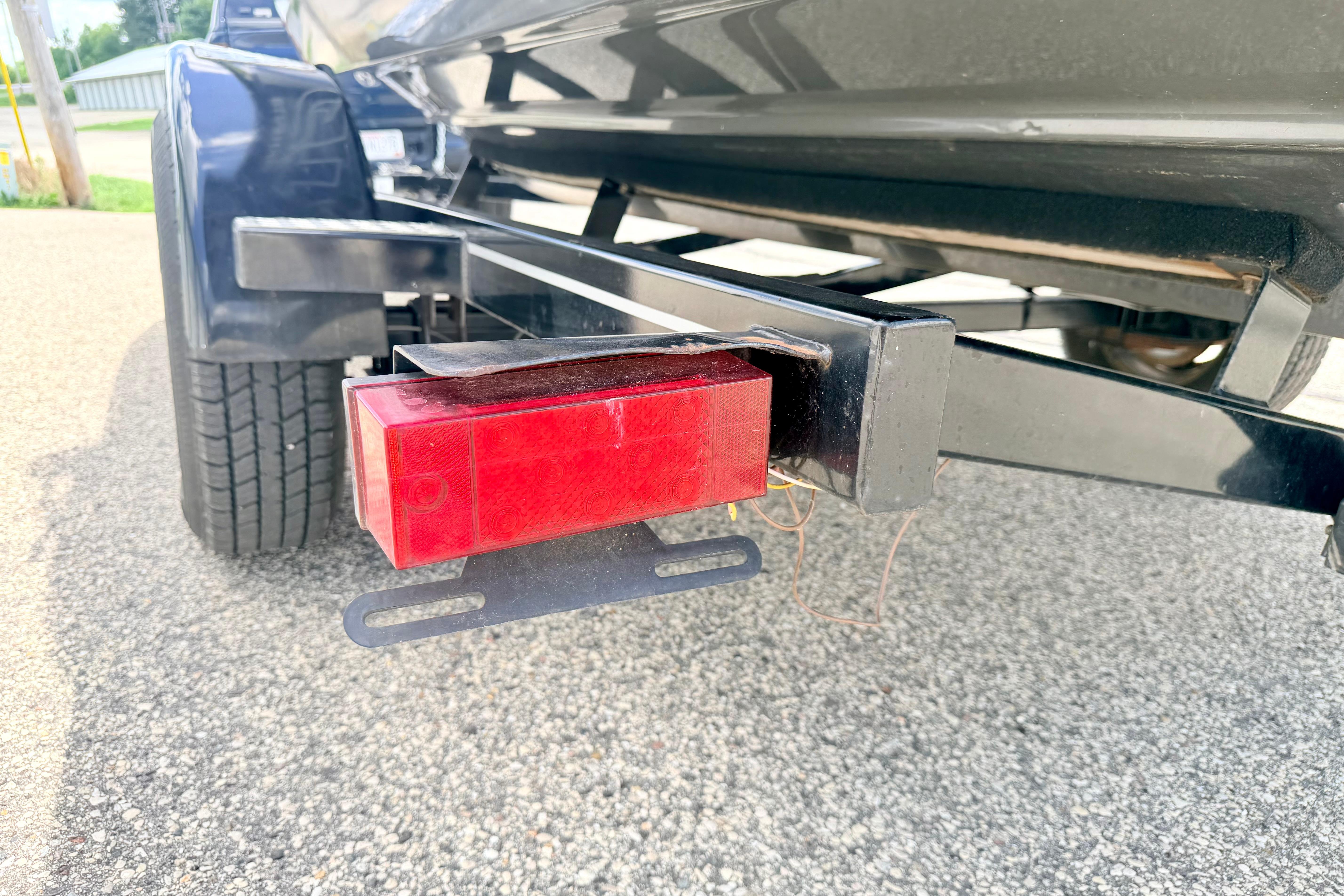 Trailer light on a 2018 Glastron GT 185 boat trailer, parked on asphalt.