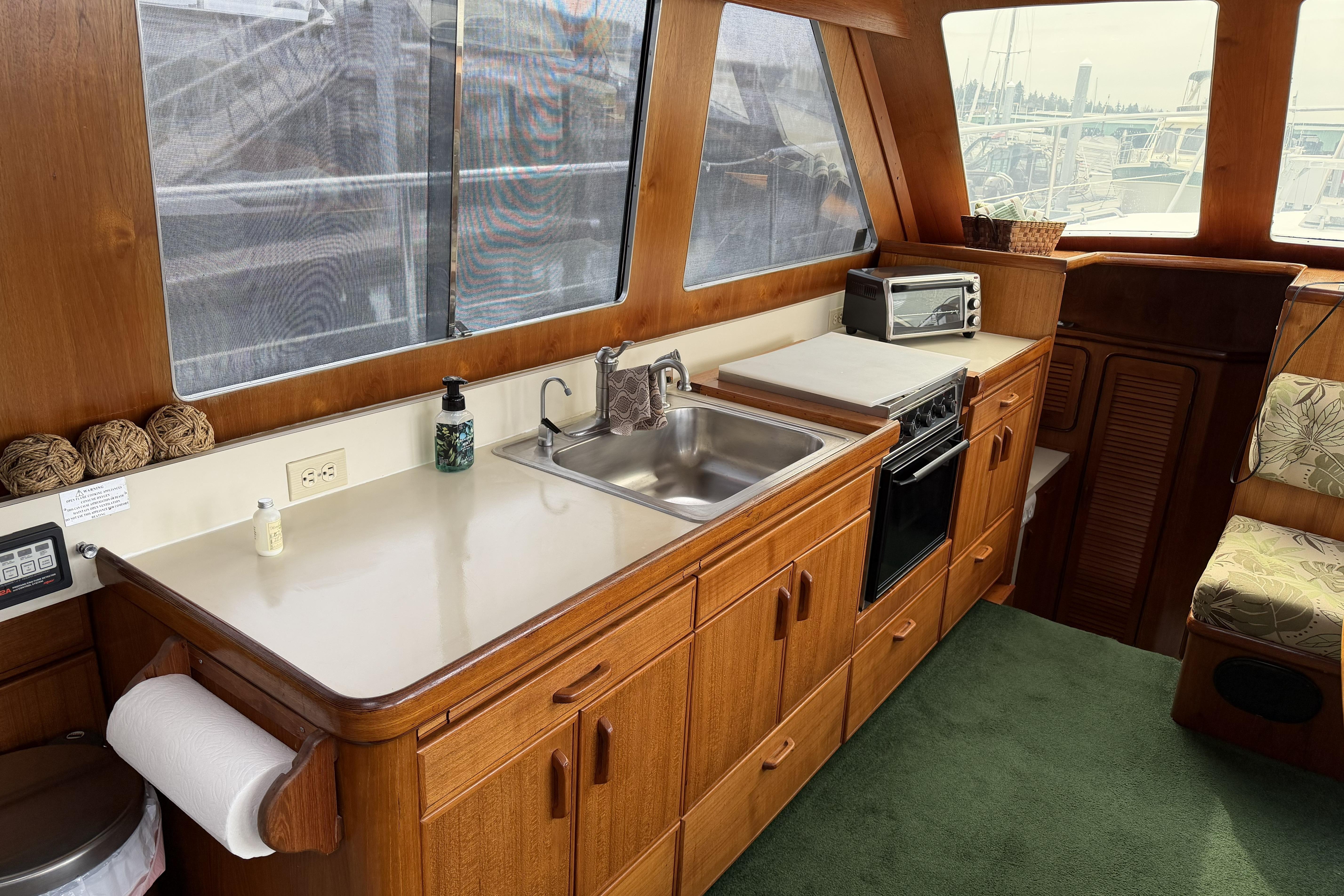 Interior of 1984 Gulfstar 49 Motor Yacht kitchen with sink, stove, and wooden cabinetry.