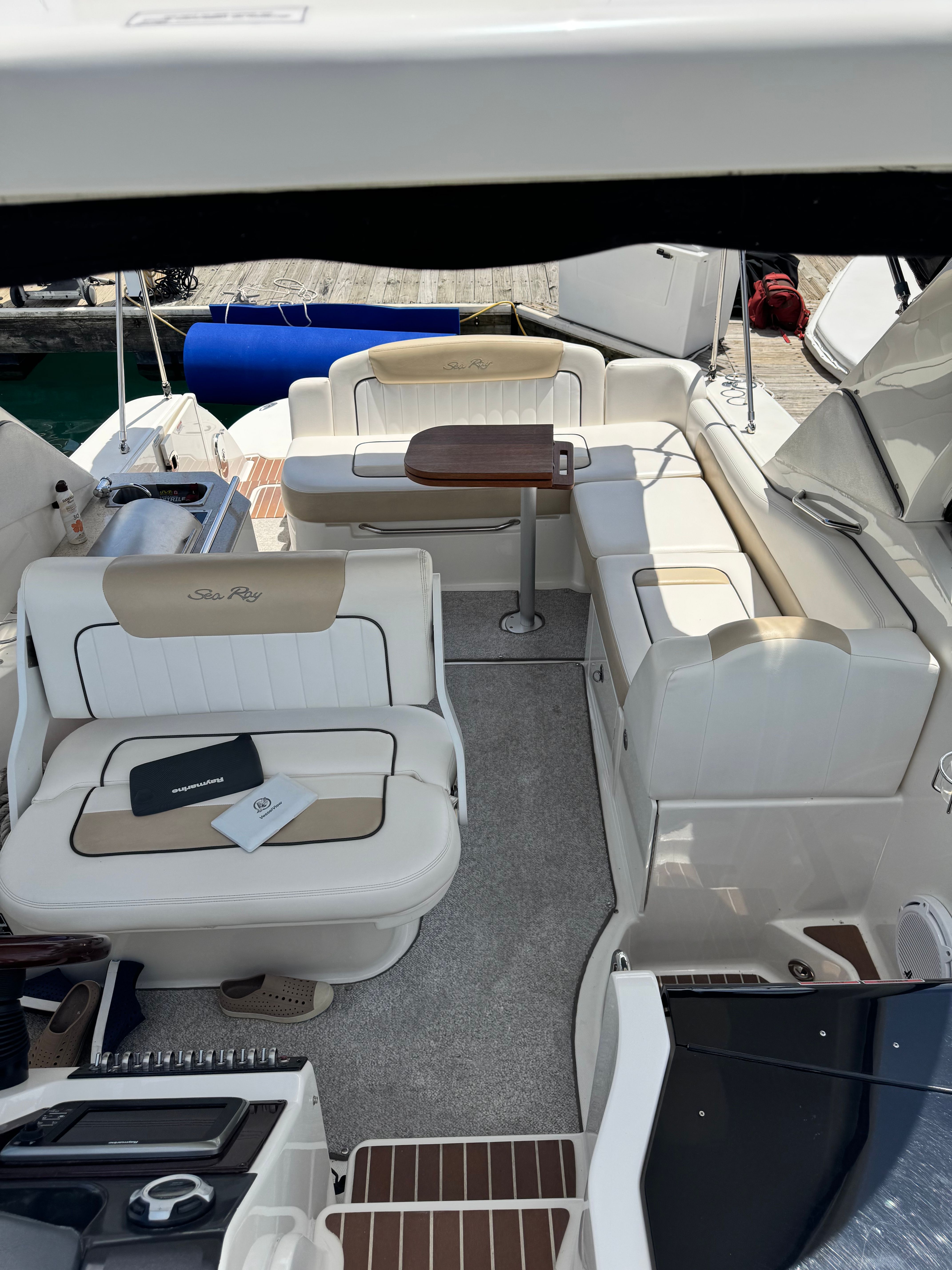 The image shows the cockpit of a 2010 Sea Ray Sundancer 310 with beige seating.