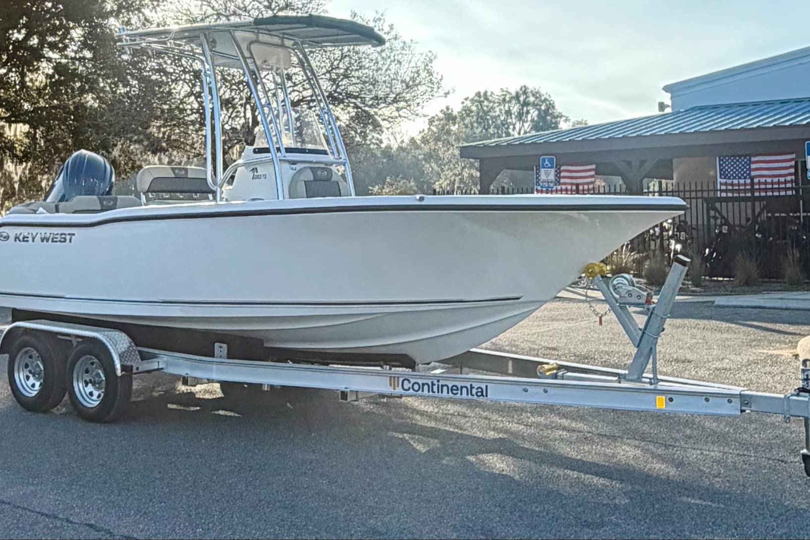 2026 Key West 203 FS boat on trailer, parked outdoors with American flags in background.