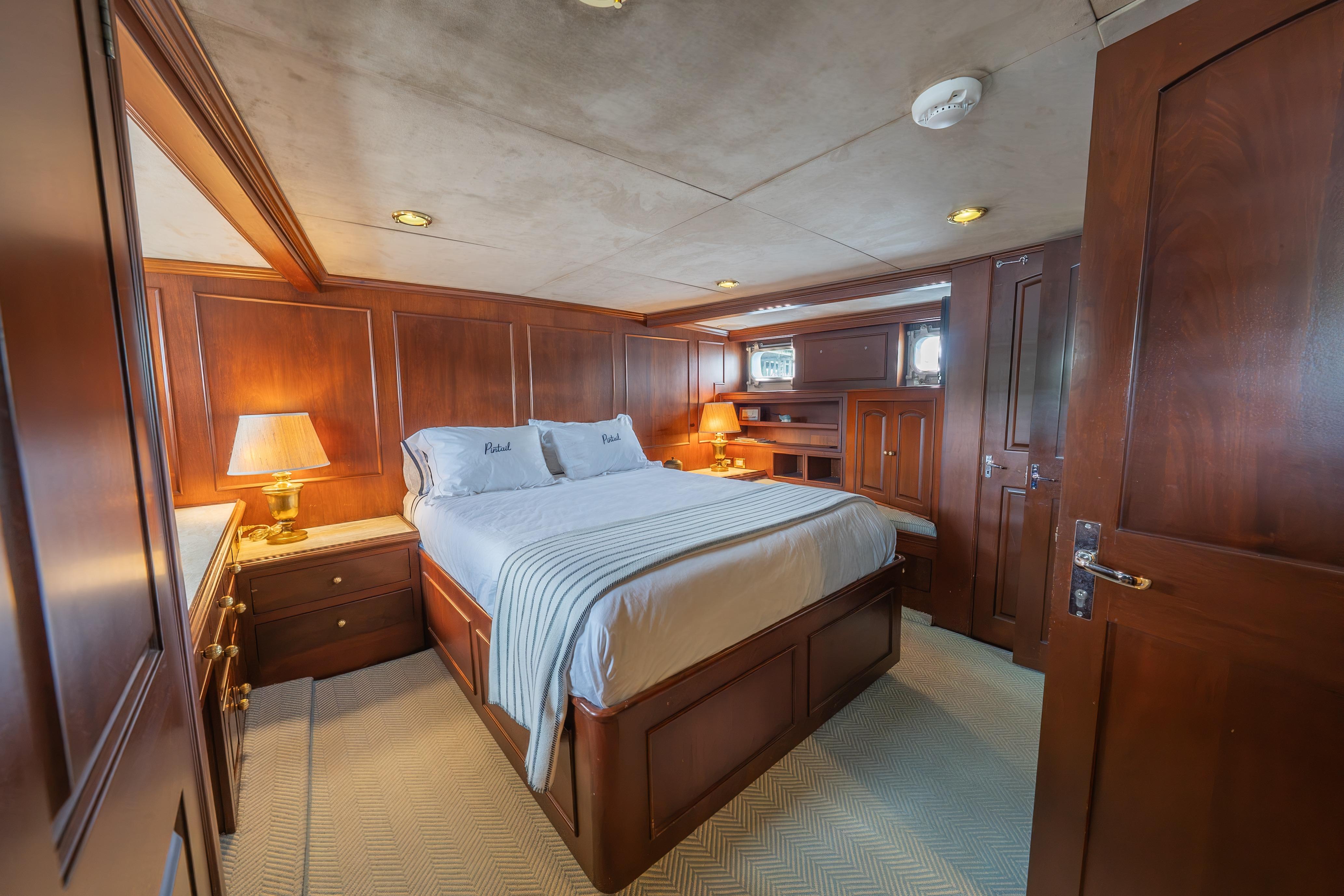 Luxurious 1963 Trumpy Classic yacht bedroom with elegant wood paneling and cozy lighting.