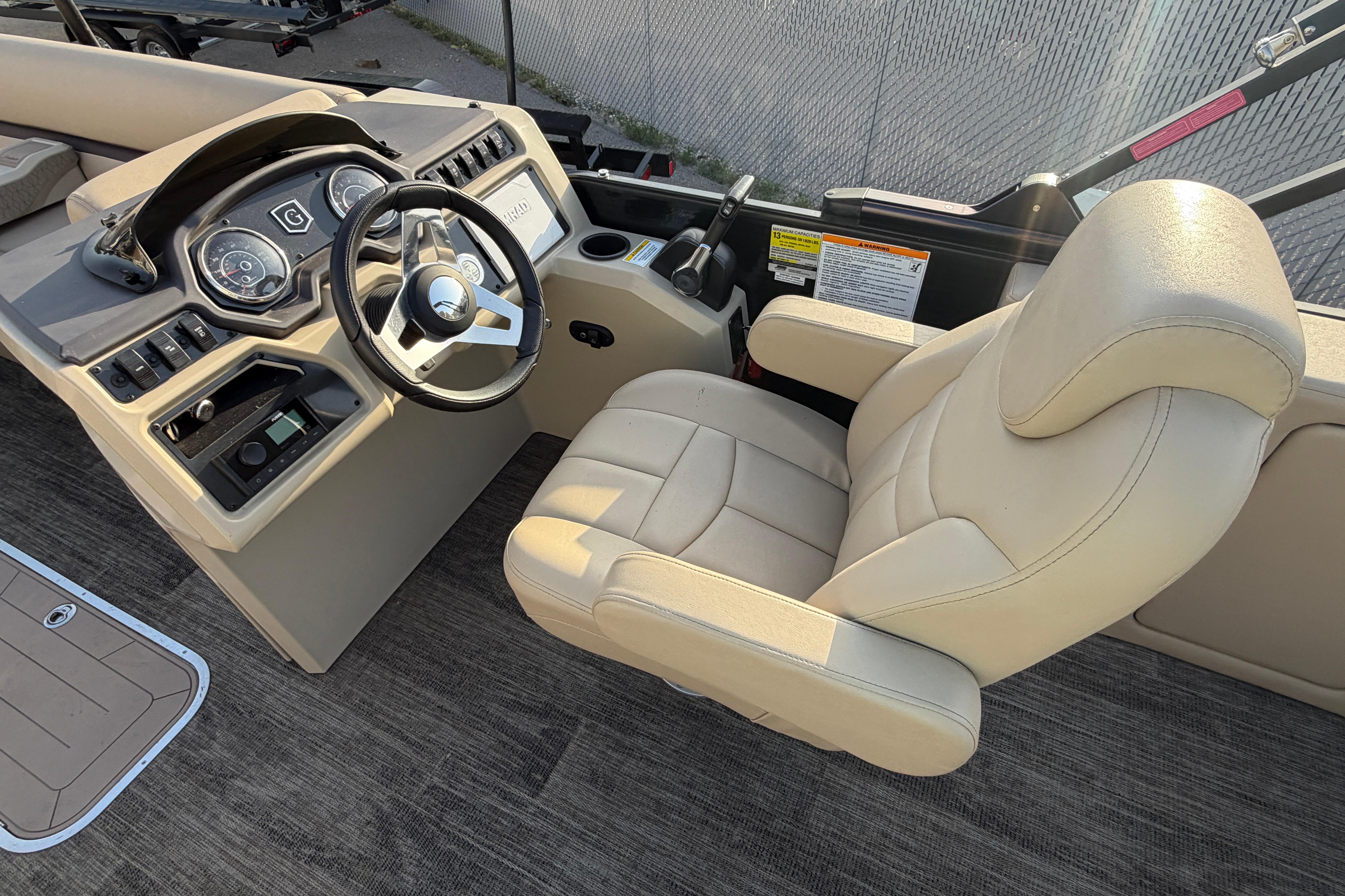 2023 Godfrey Sweetwater 2286 C boat helm with beige captain's chair and control panel.