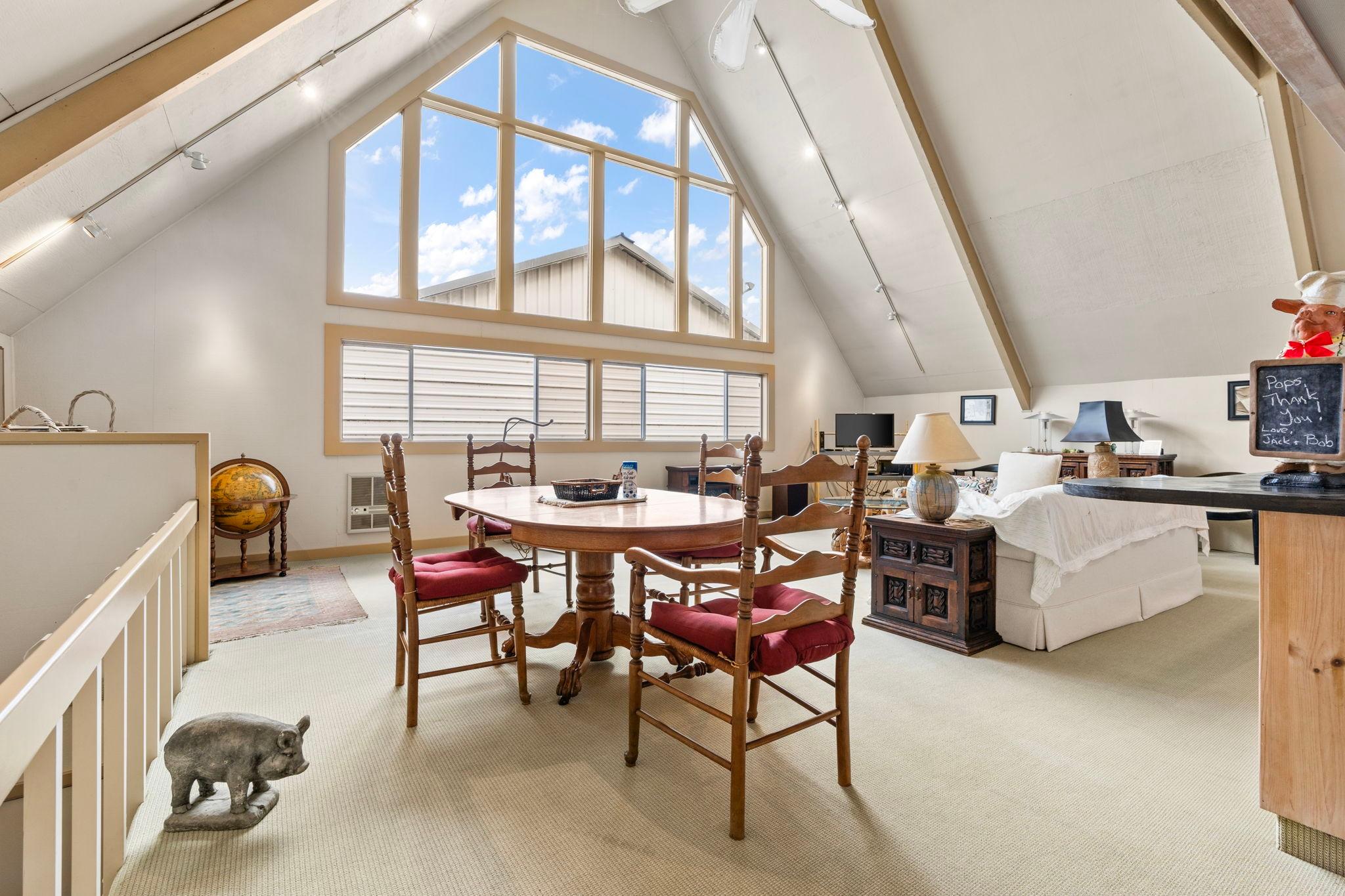 Spacious 1976 custom boathouse interior with vaulted ceilings, large windows, and elegant dining area.